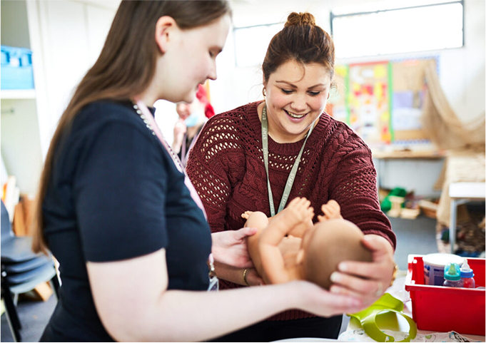 A student and lecturer holding a baby in the Early Years and Schools unit at Boston College.
