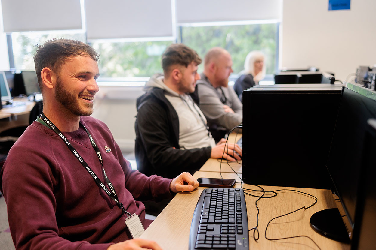 A smiling student working at a computer.