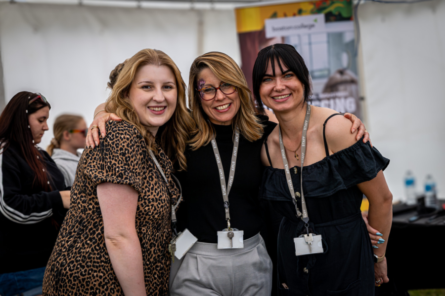 Three staff members stood smiling at an event.