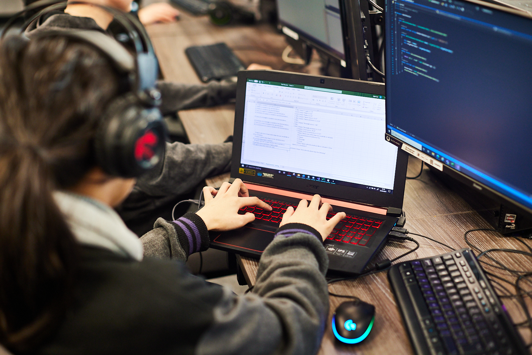 Student with headphones on working at a laptop.