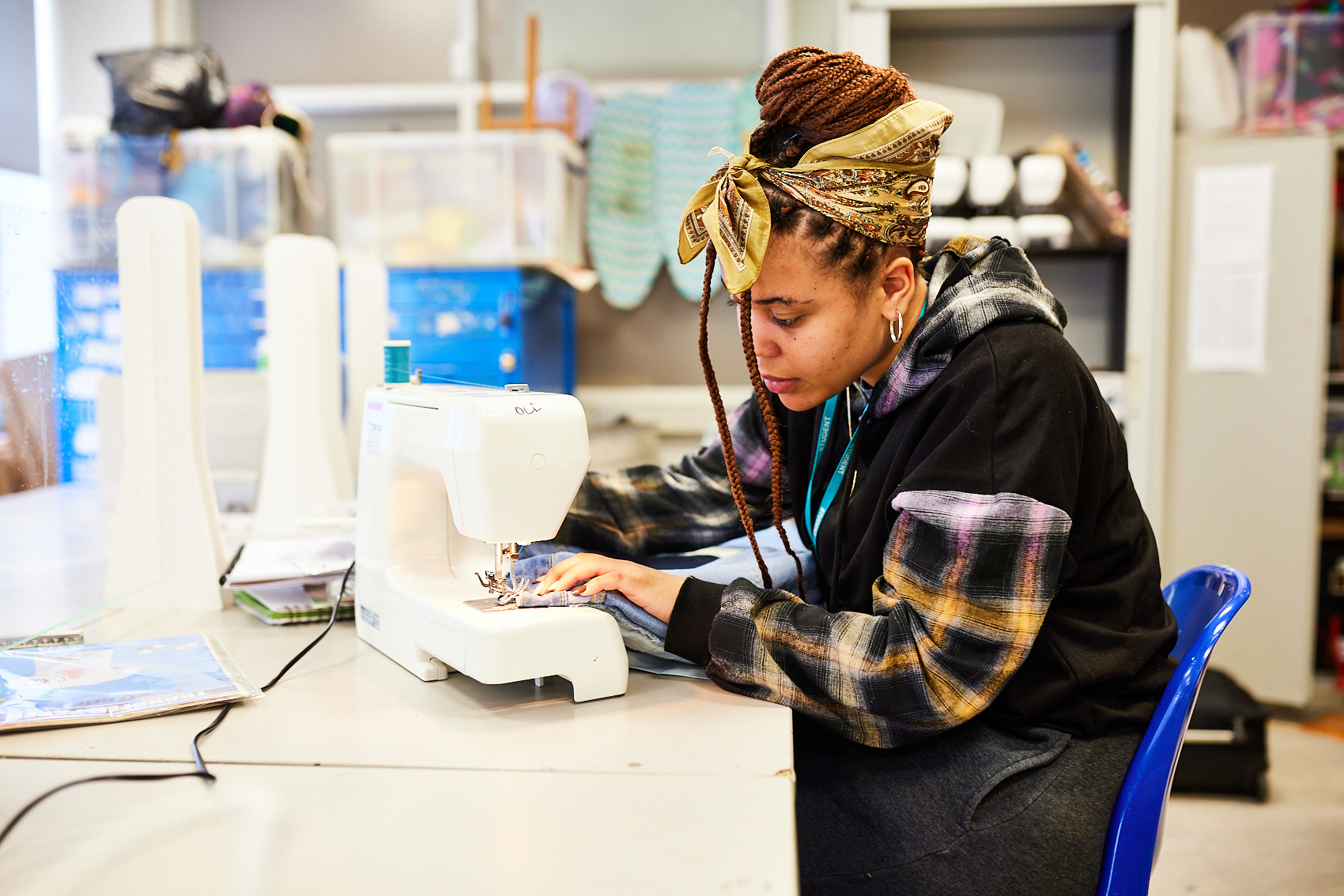 A student using a sewing machine in a classroom.