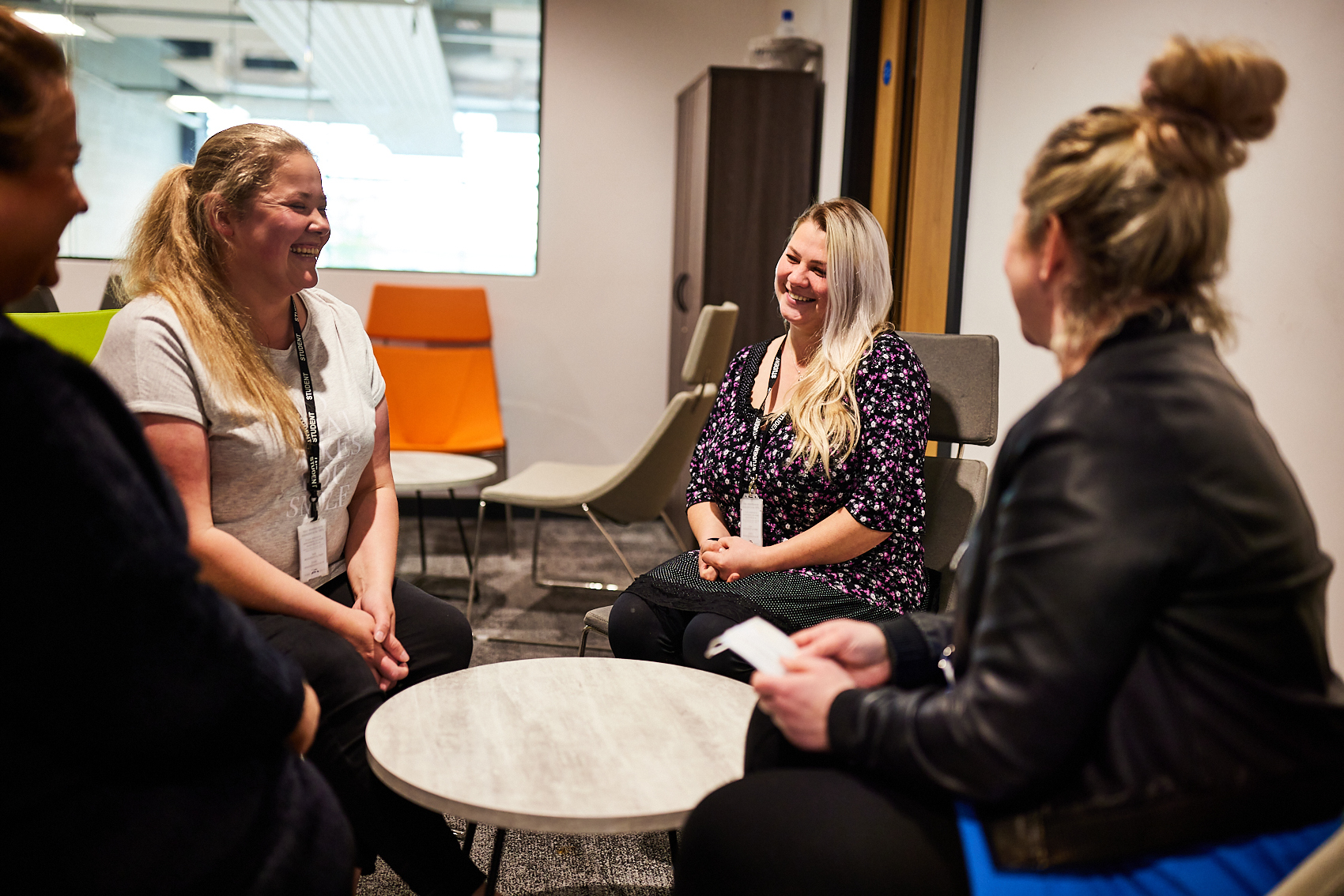 Group of students talking and laughing around a table.
