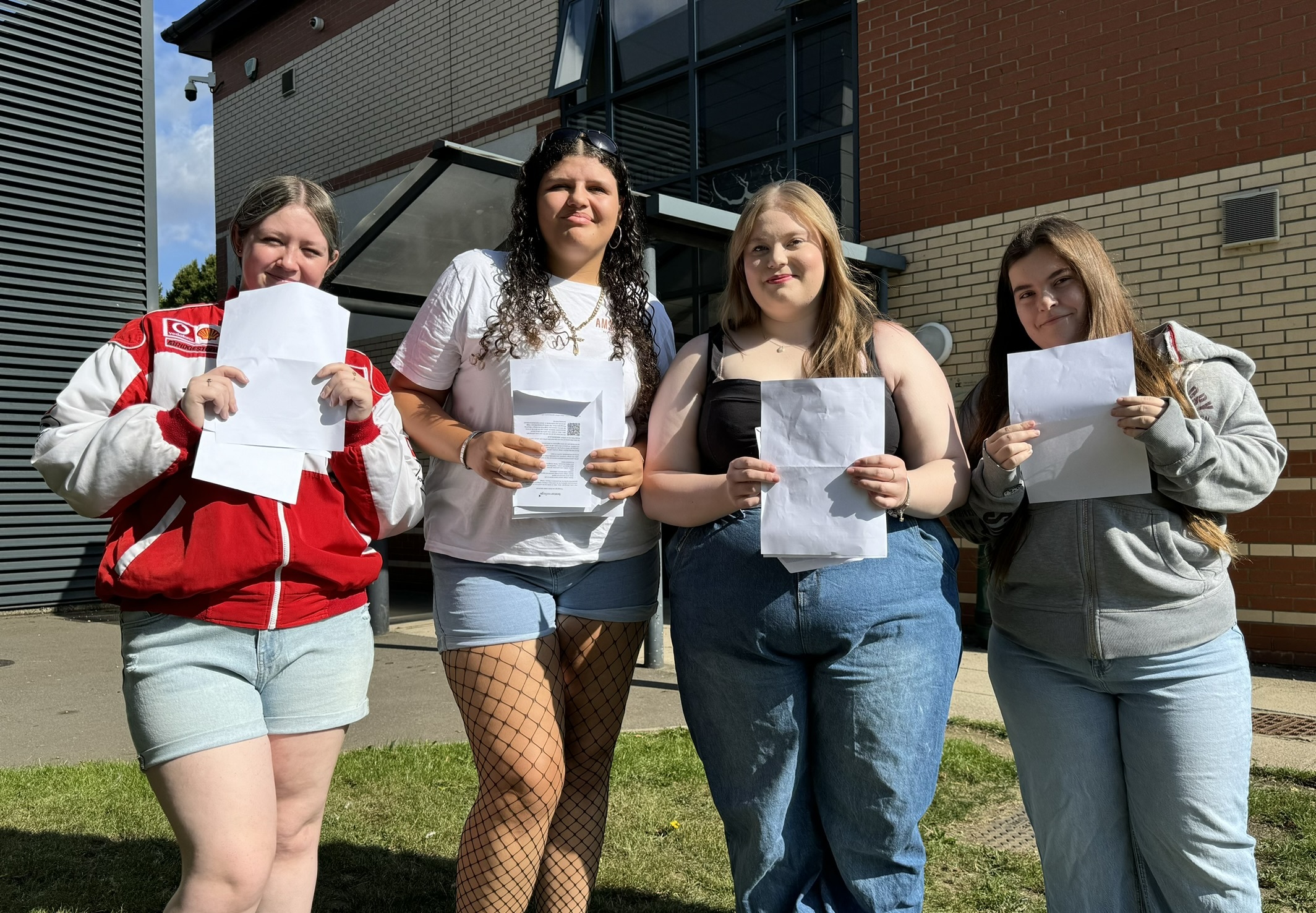 Group of students holding their A-Level results papers.