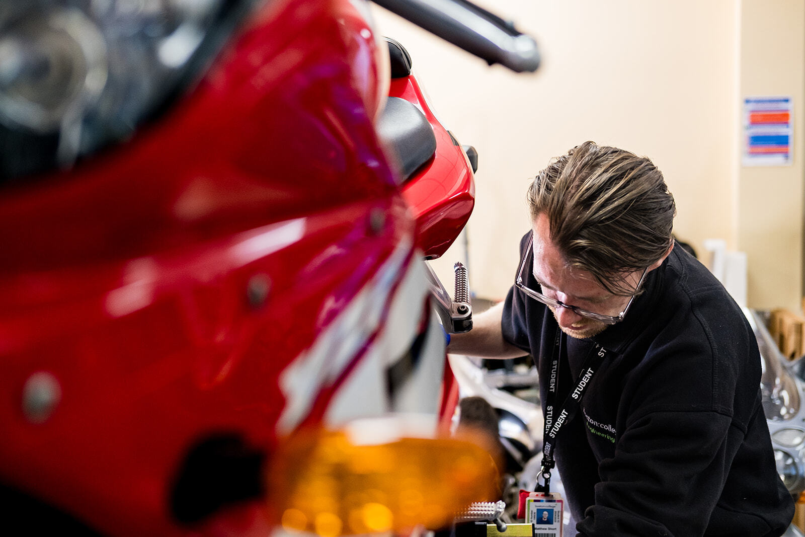 A student looks down while carrying out work on a motorcycle.