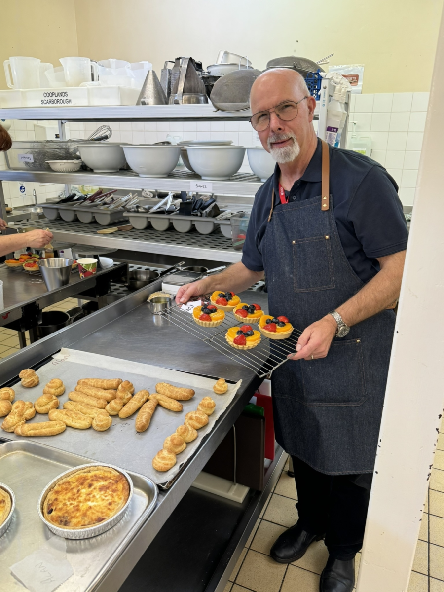 A student displaying food that they have made in a kitchen.