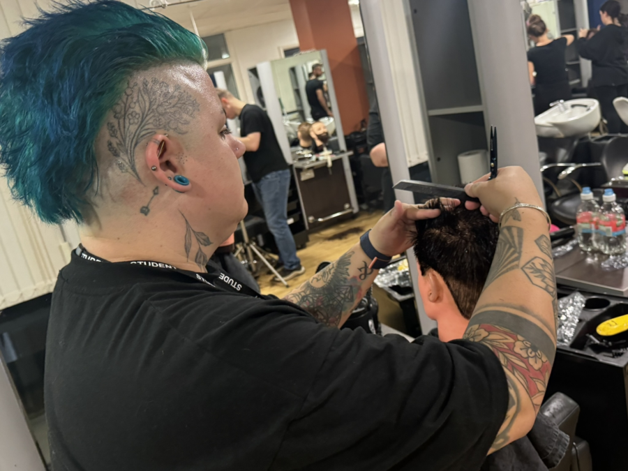 A student with blue hair cutting hair.