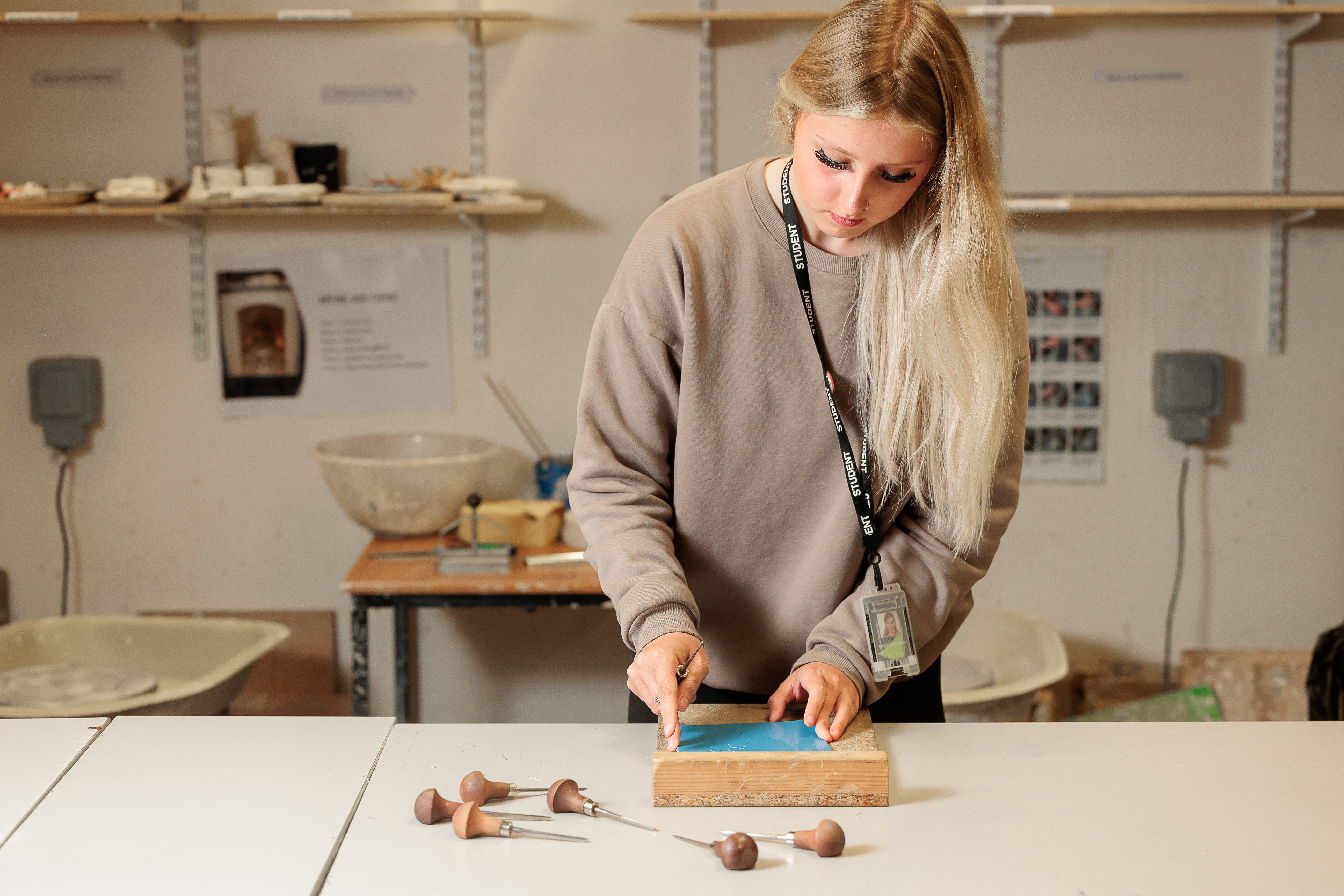 Student carving a wooden art piece.