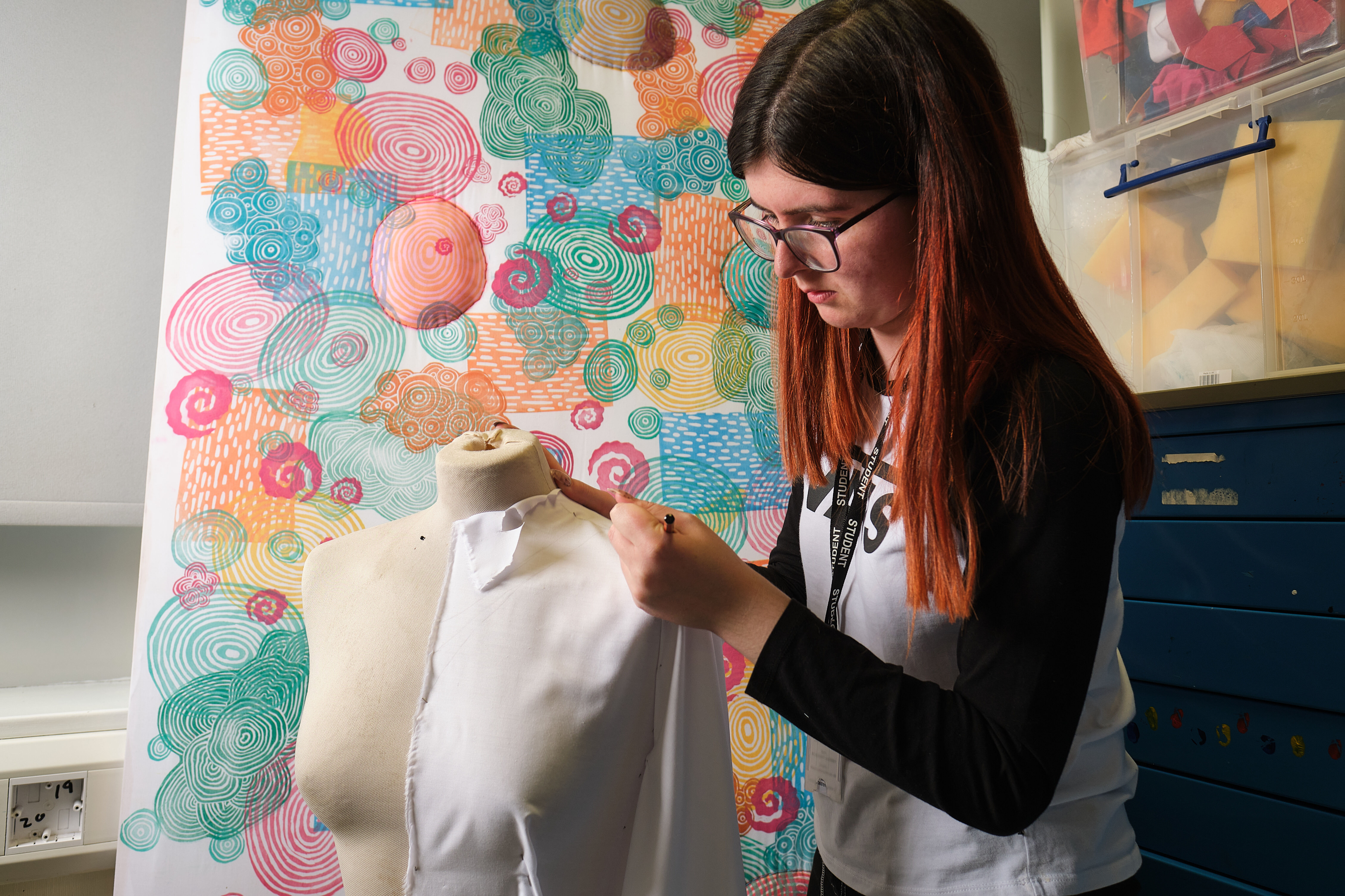 Student pinning fabrics to a mannequin.