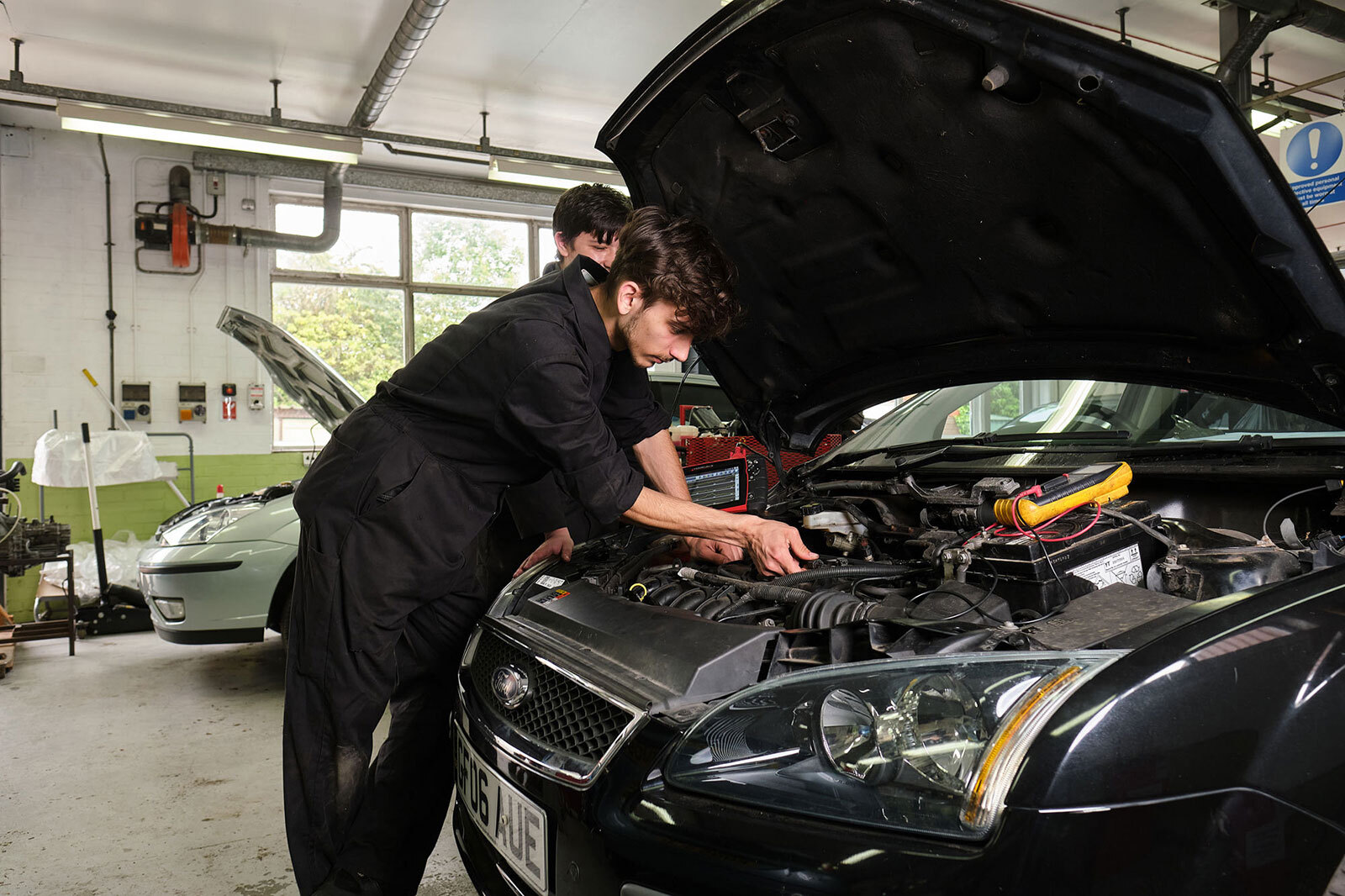 Student using tools on a car engine.