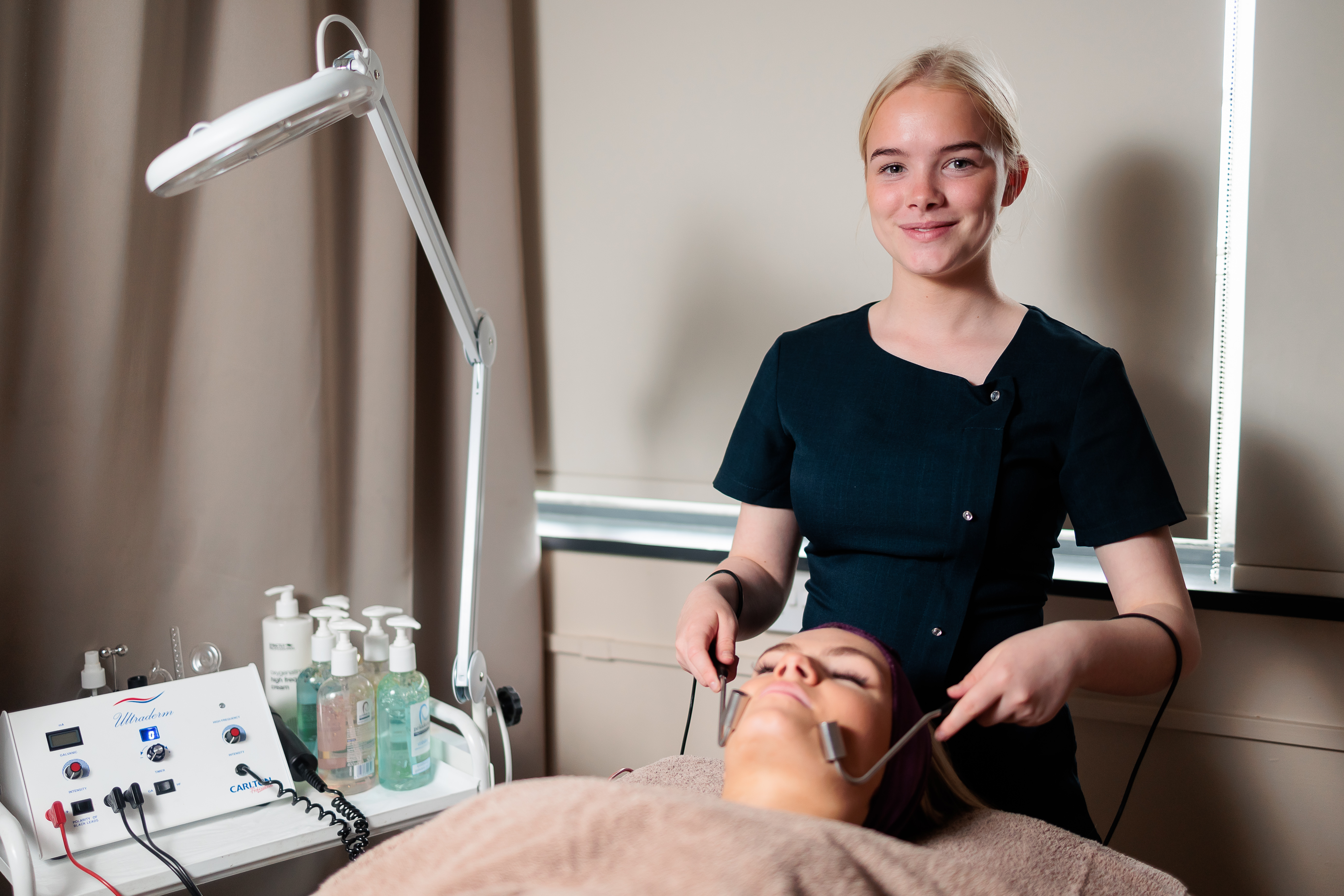 Student looking at the camera while giving a facial massage with massage tools.