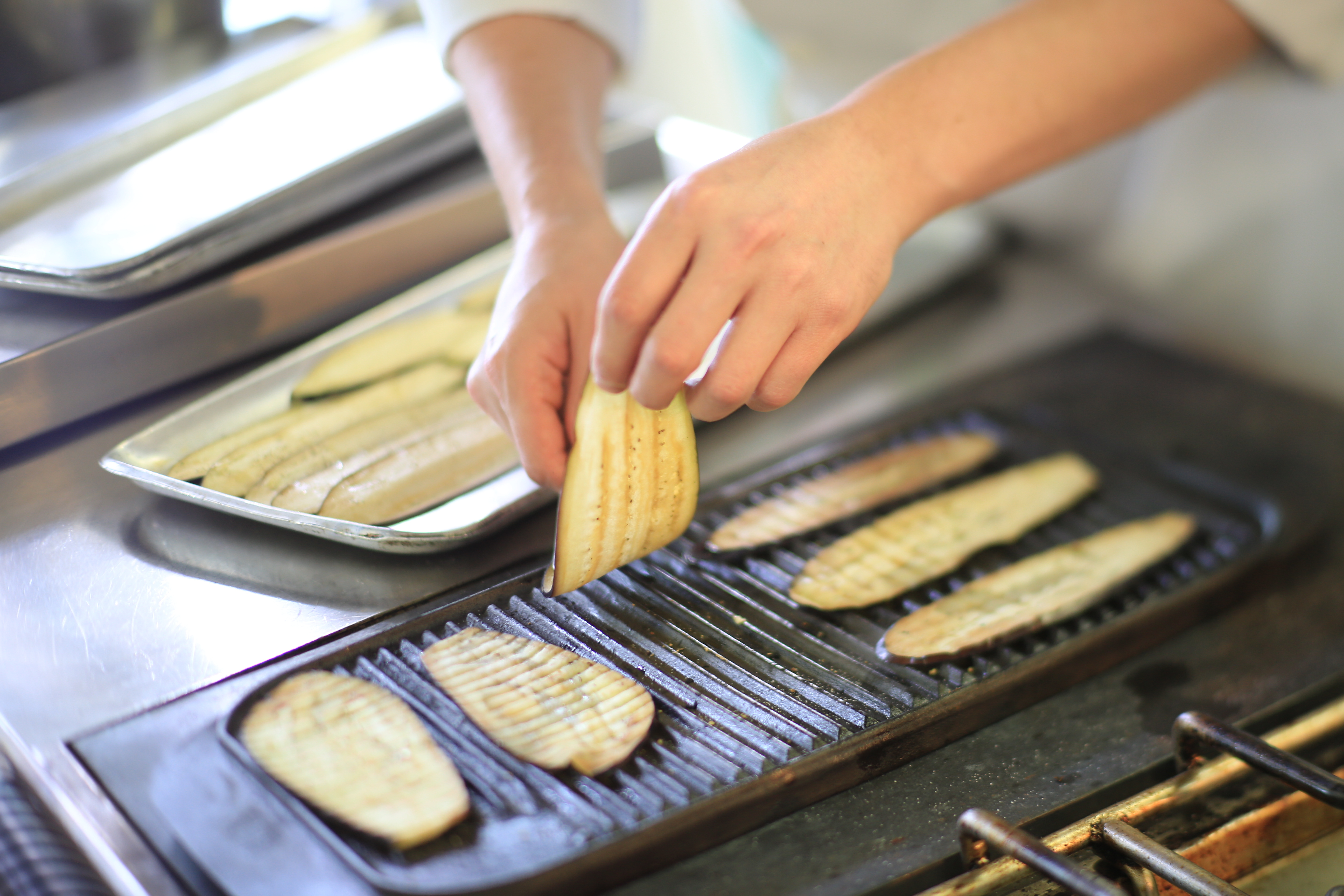Student chef preparing food on a grill plate.