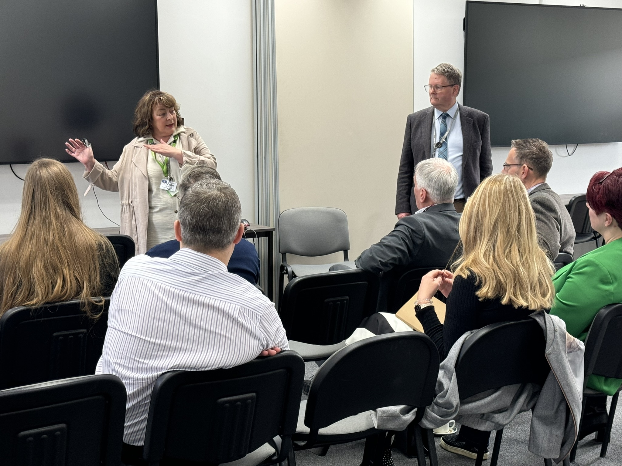 Two people giving a talk to a group of visitors.