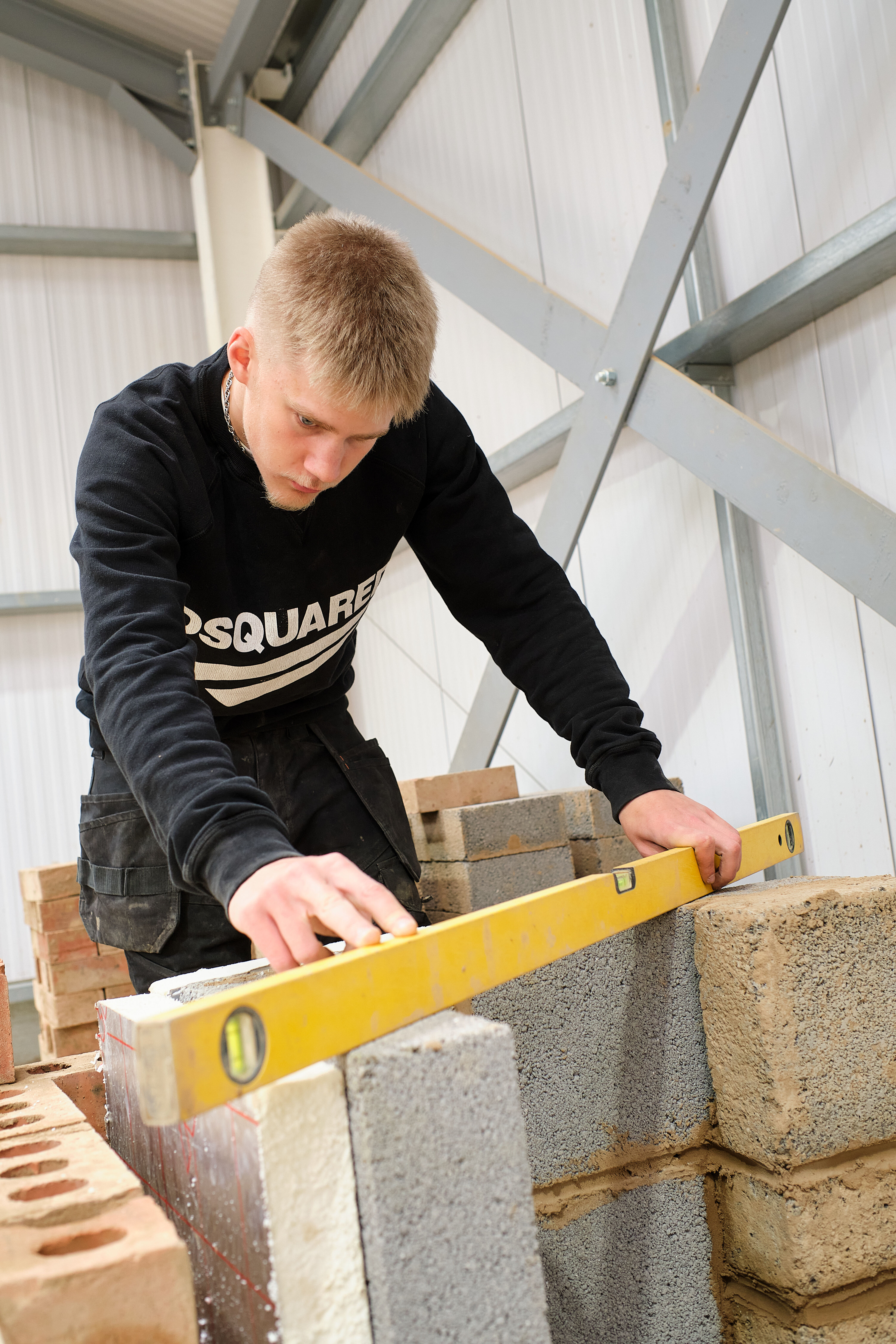 Student using a spirit level while building a wall.
