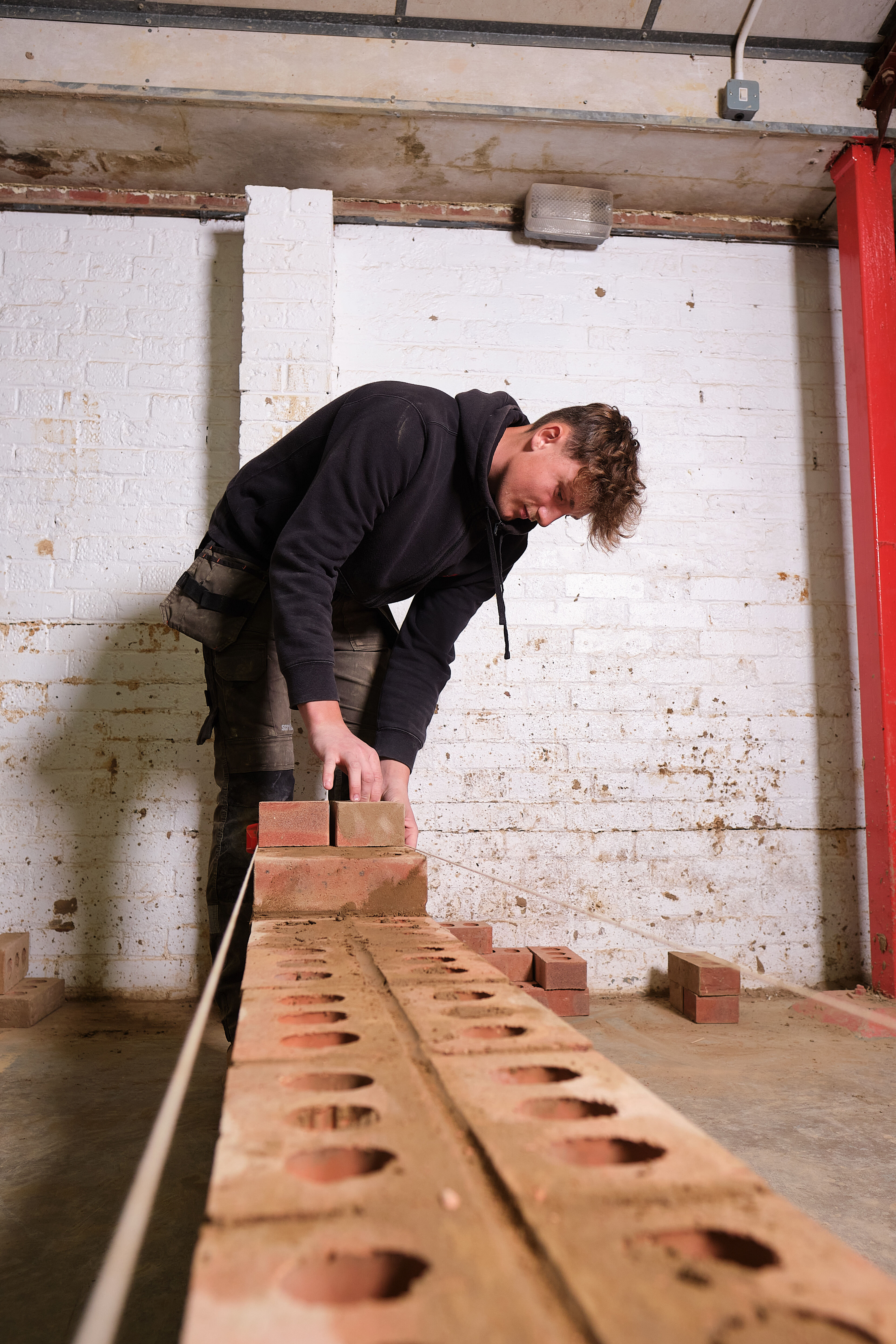 A student building and measuring a brick wall.