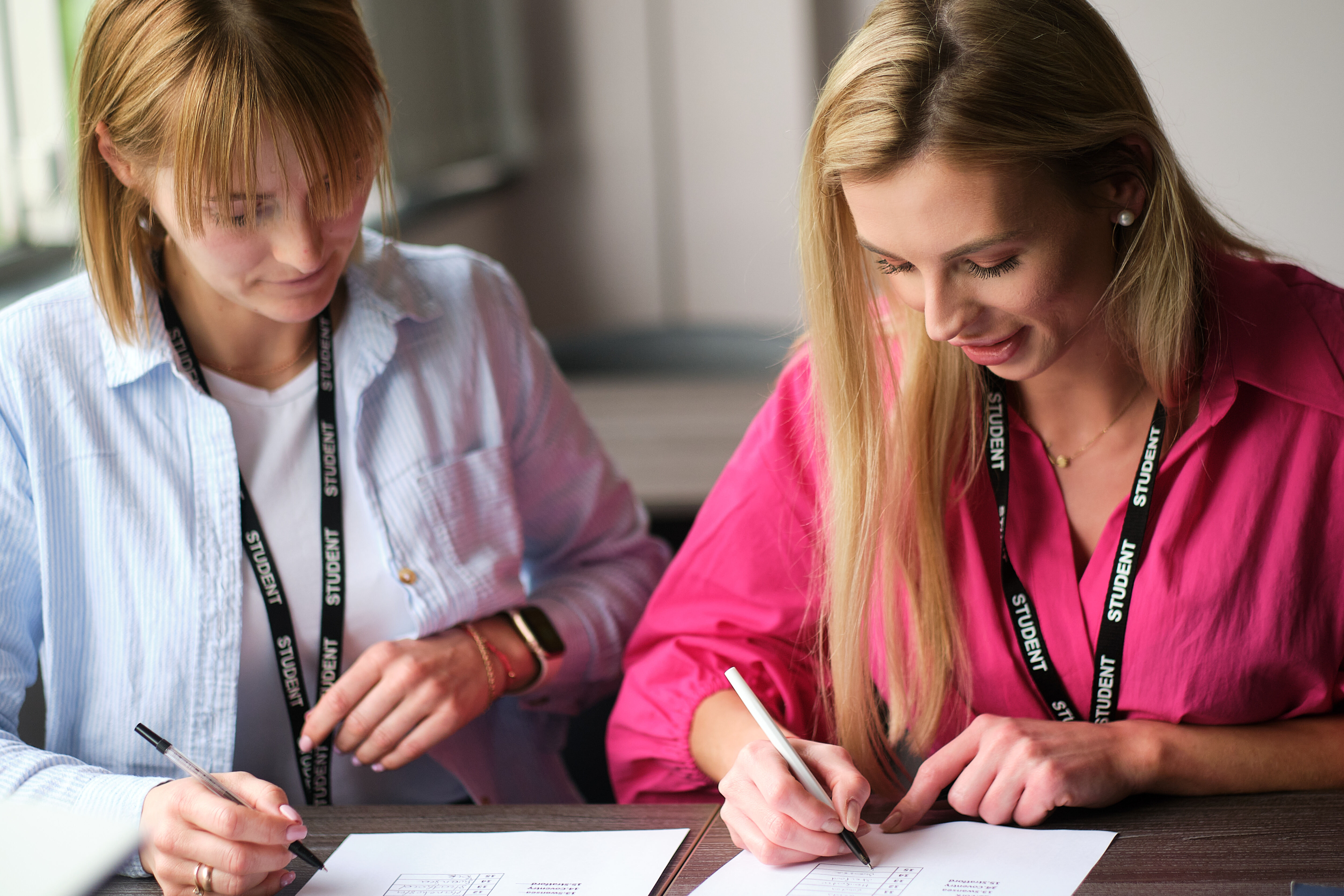 Two students sitting at a desk writing.