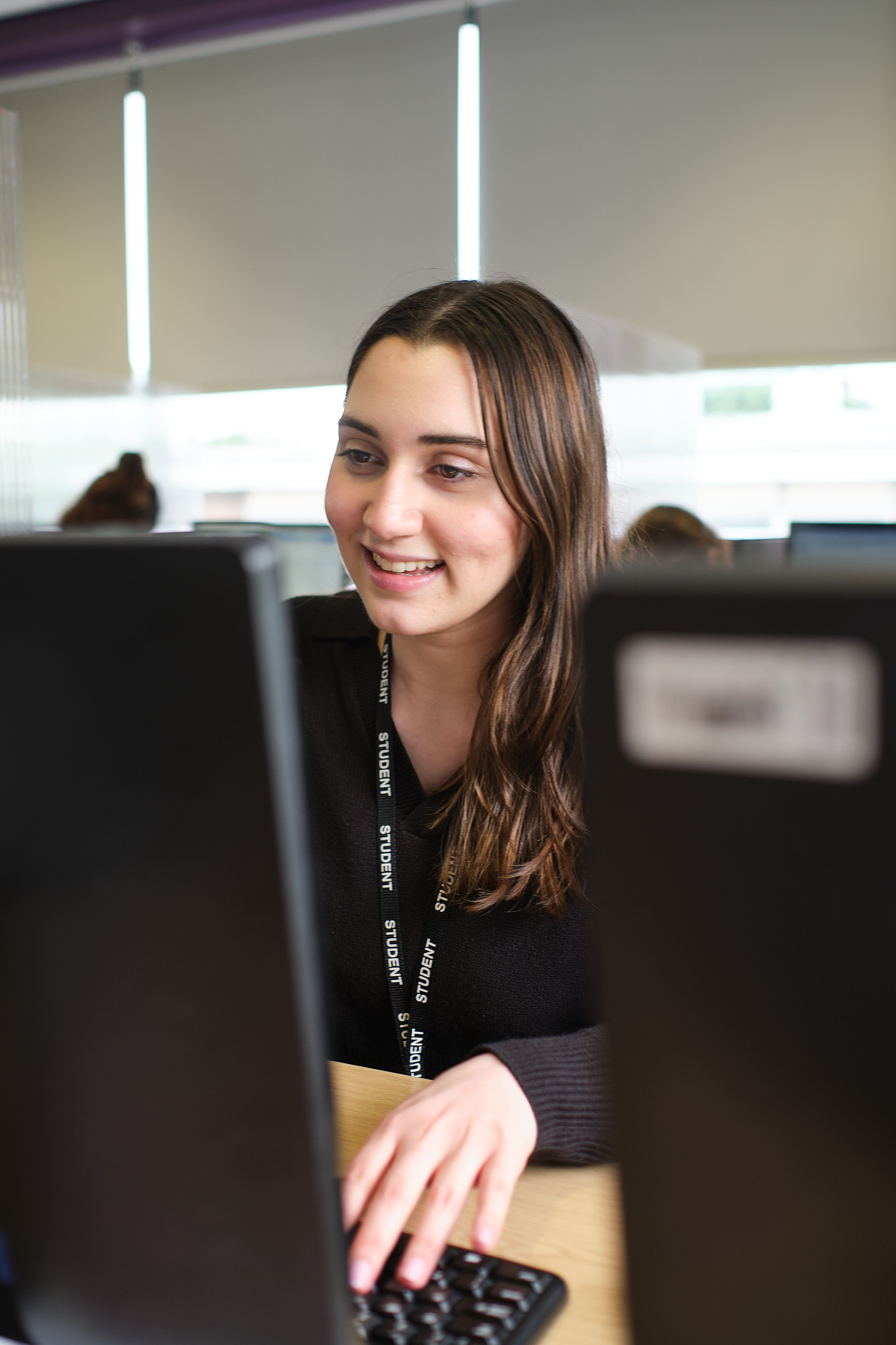 Student smiling while working on a laptop.