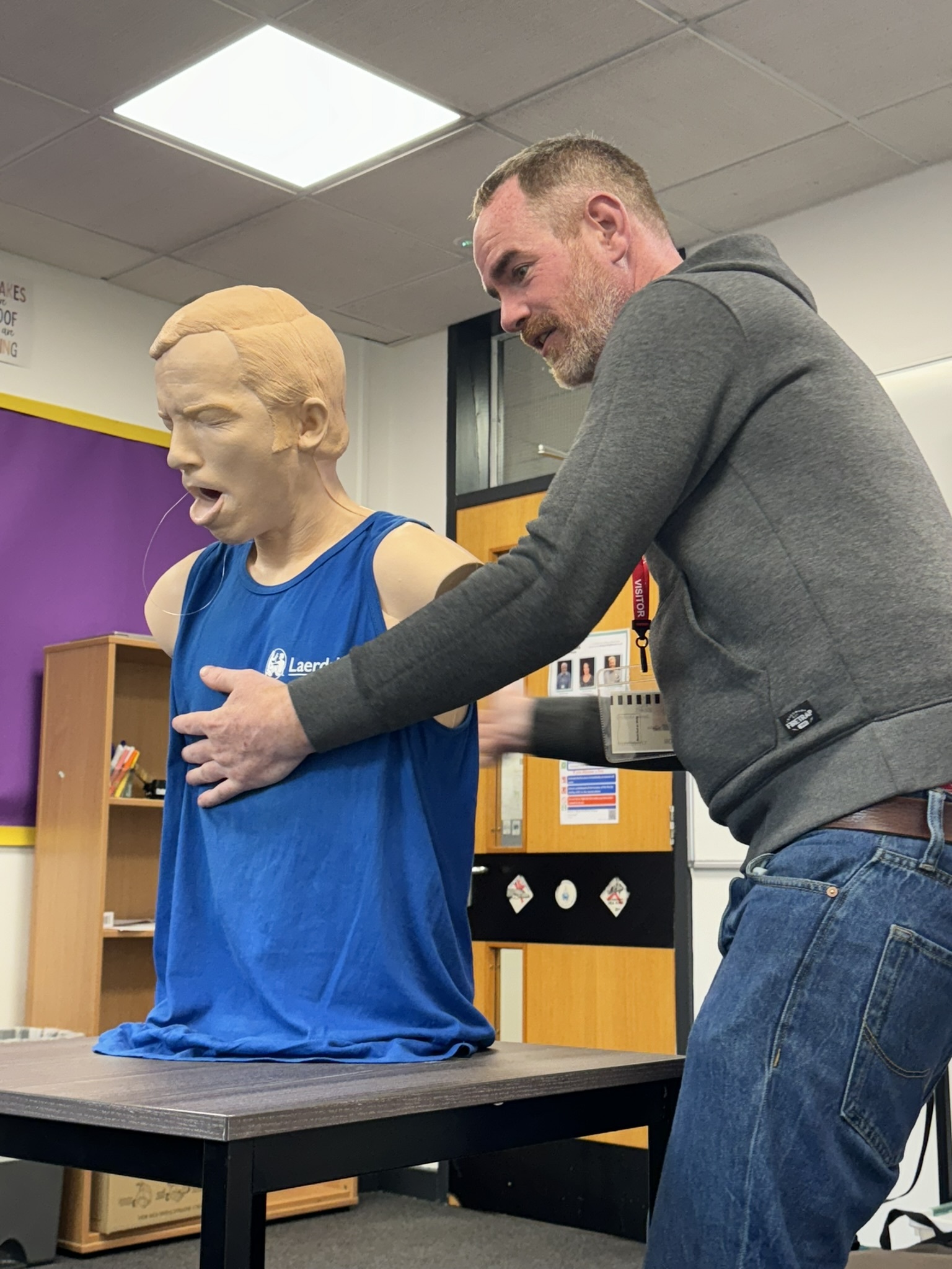 Person performing emergency first aid on a practice dummy.