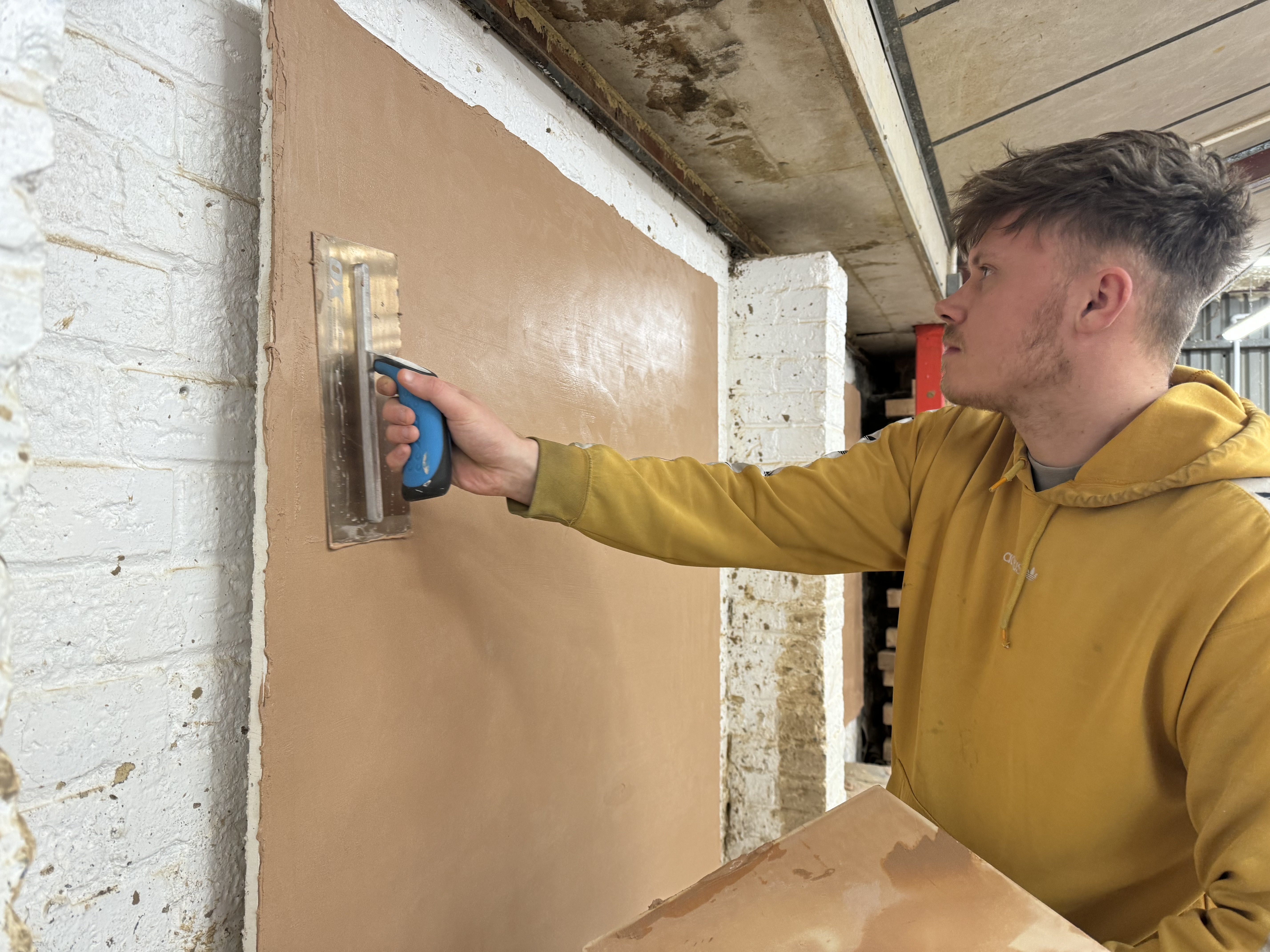 A student plastering a wall.