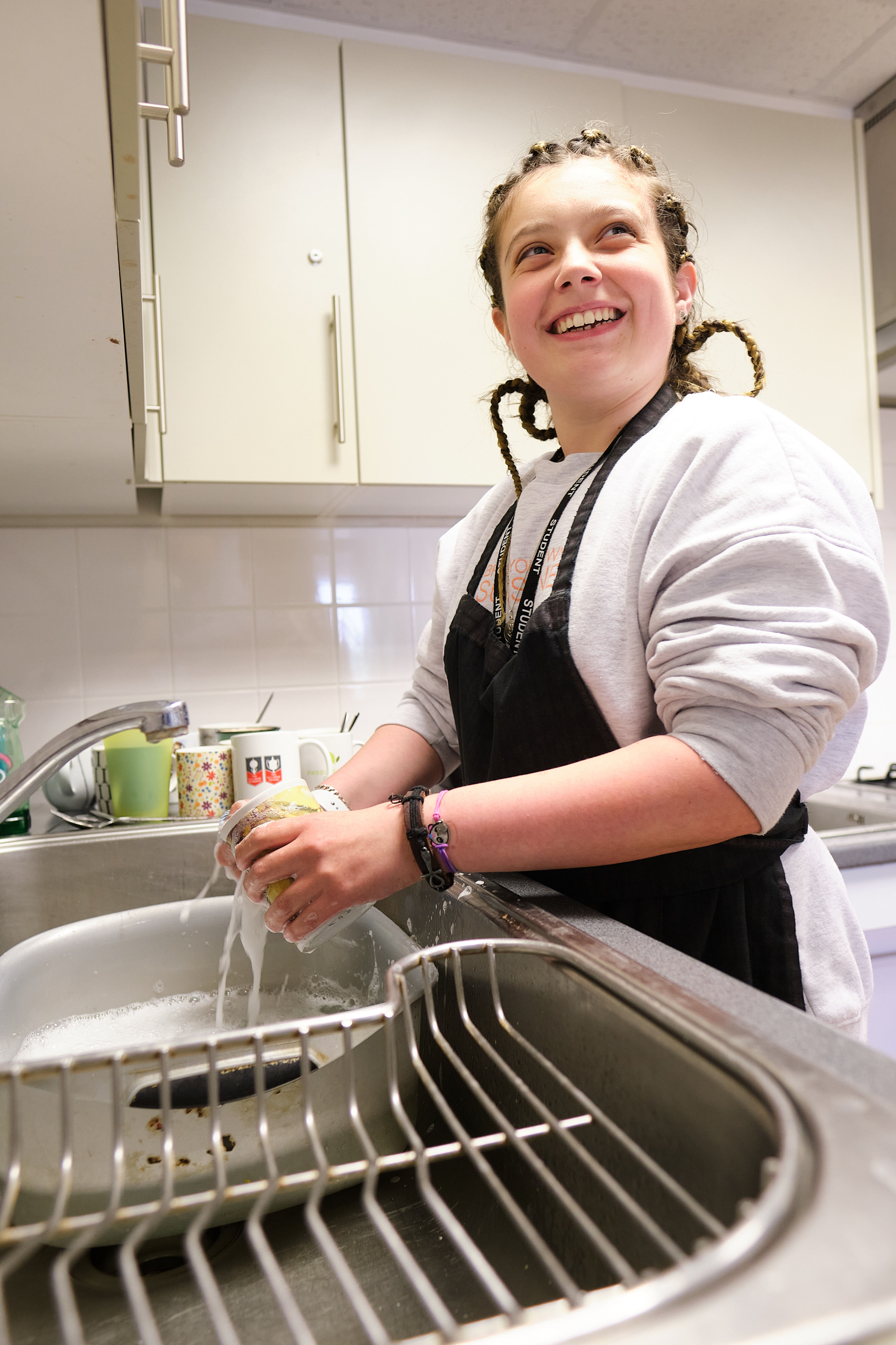 A student washing up in a kitchen.