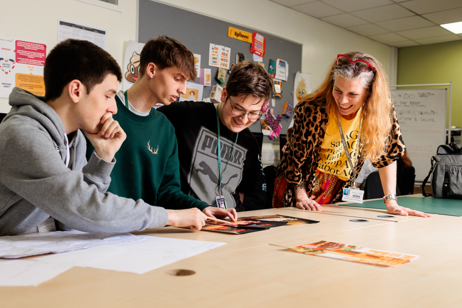 A group of students and a lecturer review some paperwork on a table.