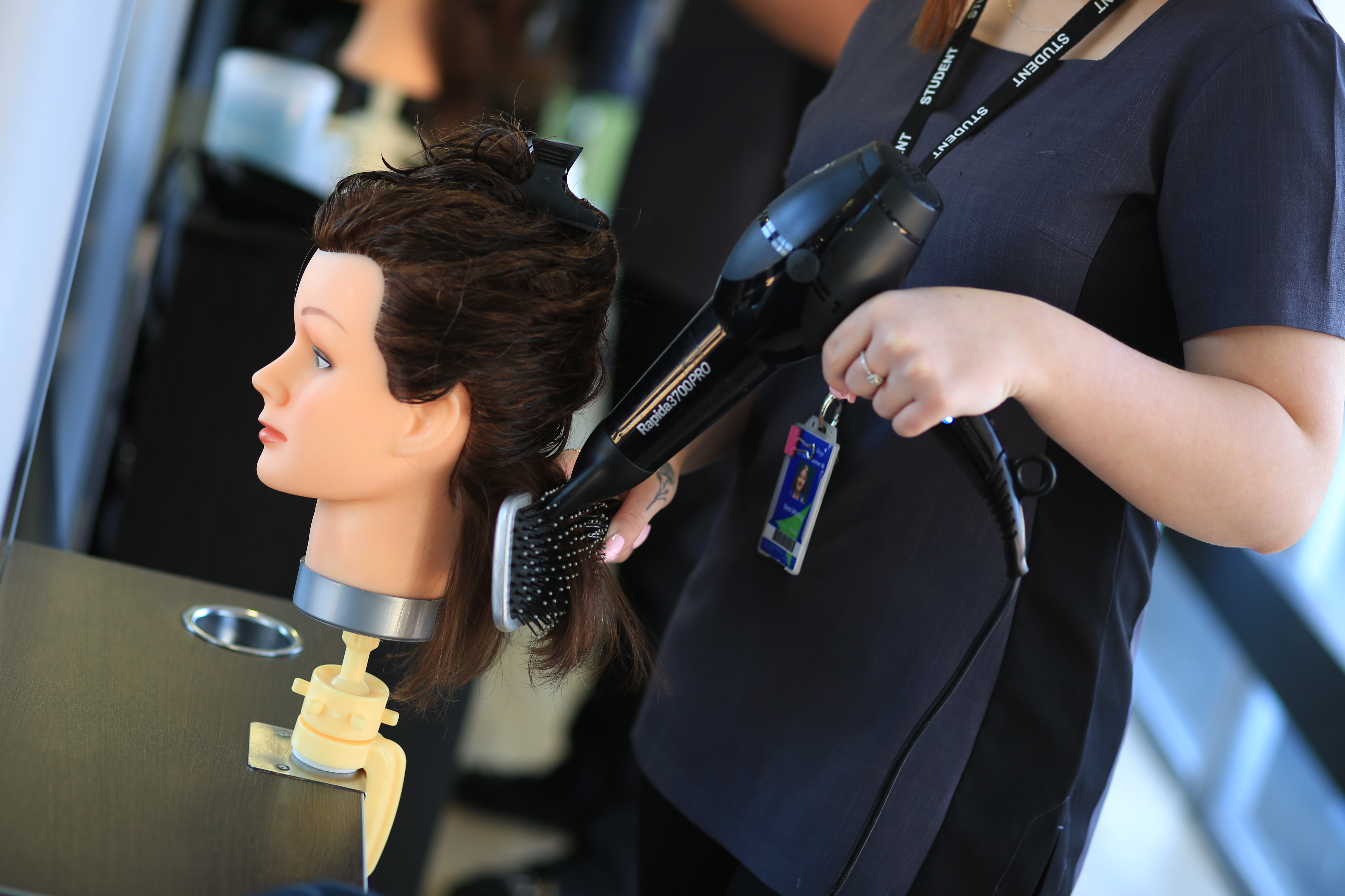A student brushing hair in the salon.
