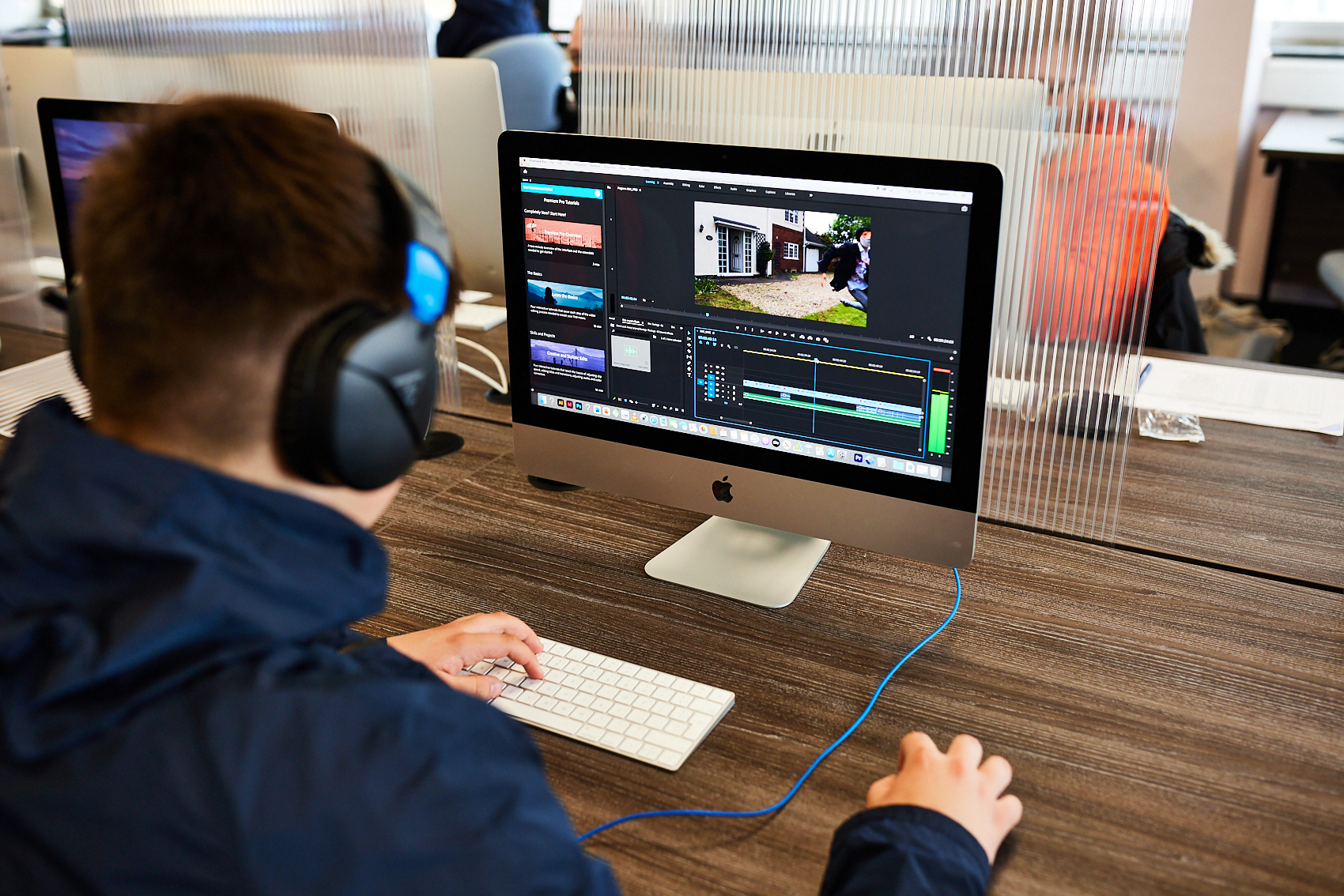 Media student with headphones works at a computer.