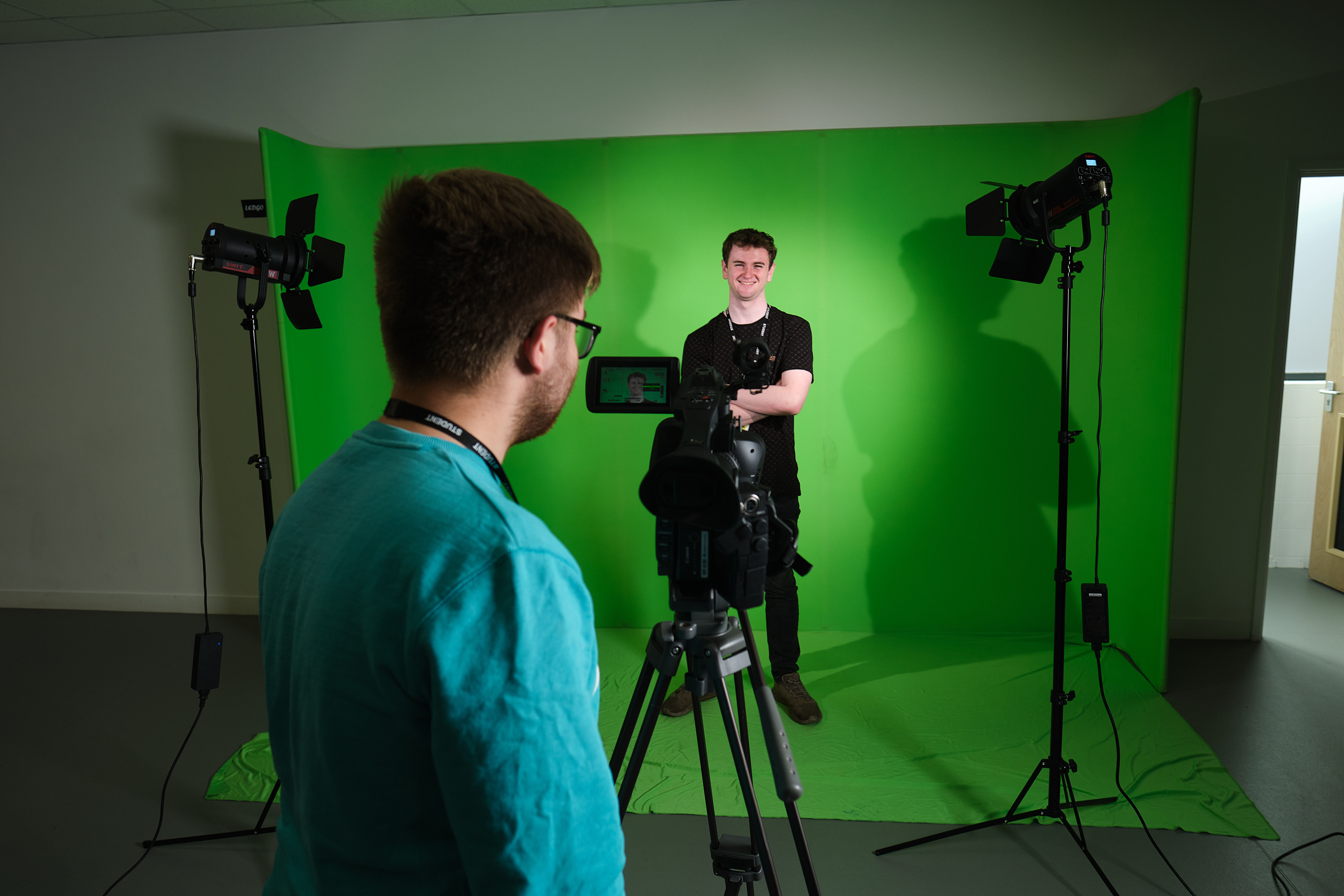 Students filming a production in the TV studio with lighting and greenscreen.