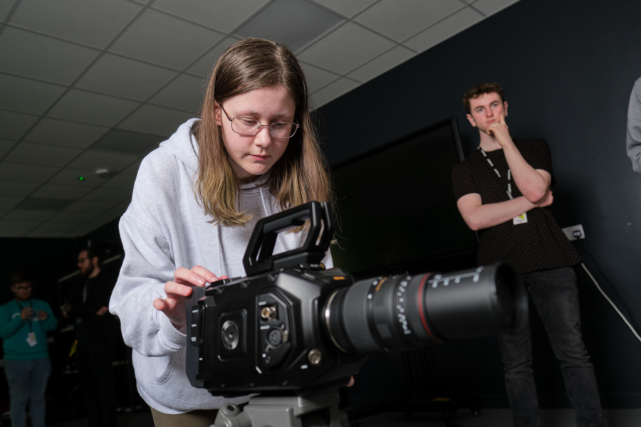 Two students make adjustments to their camera setup in the TV studio.