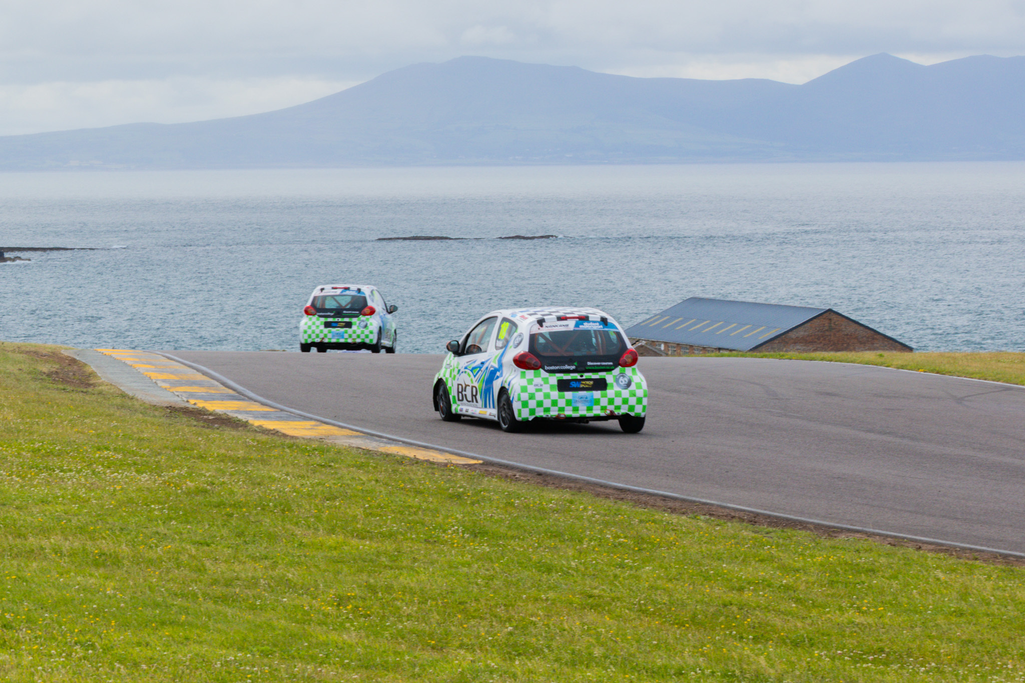 Boston College Racing Cars competing at a track close to the sea in the background.