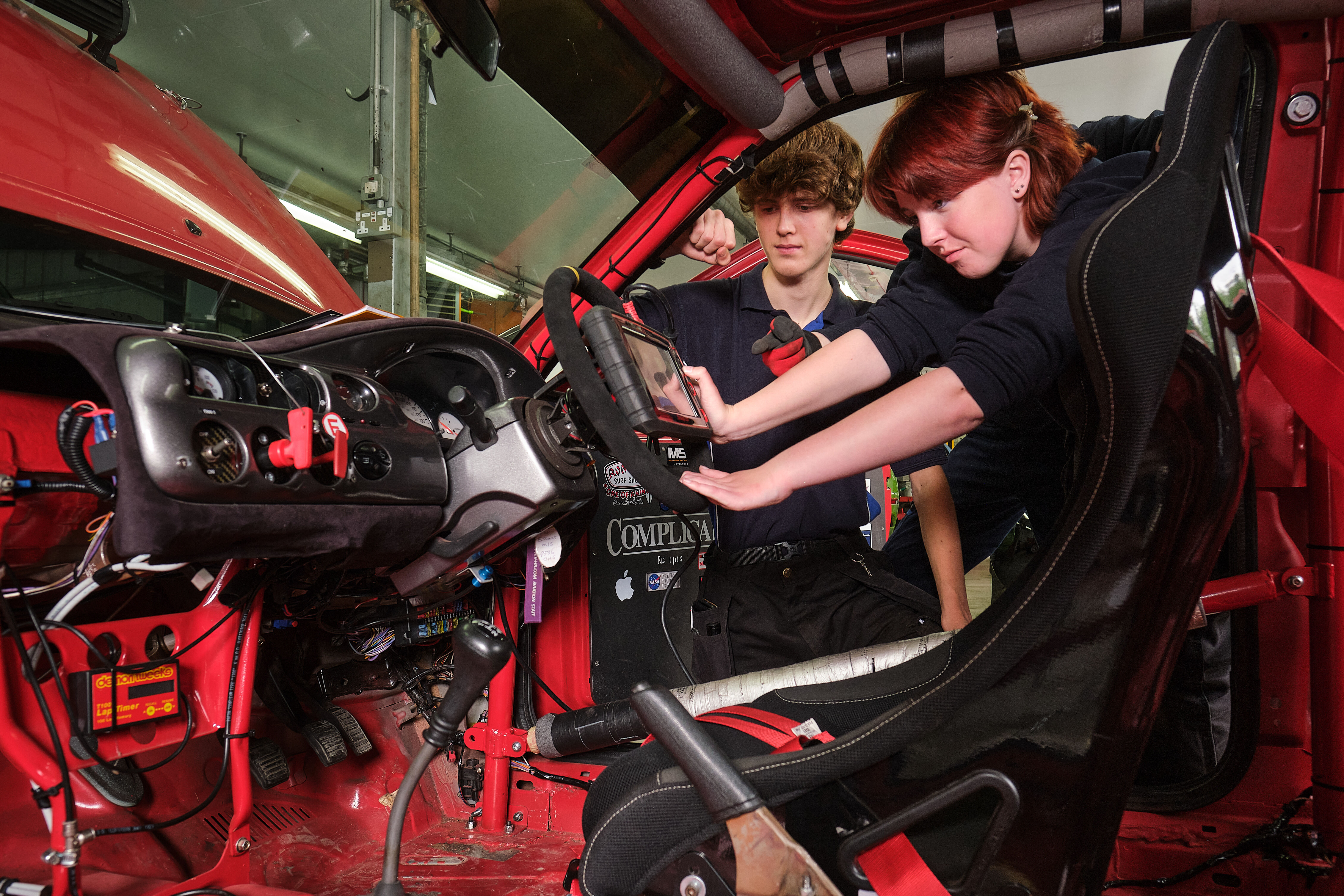 Two students working on a steering wheel in one of the race cars.