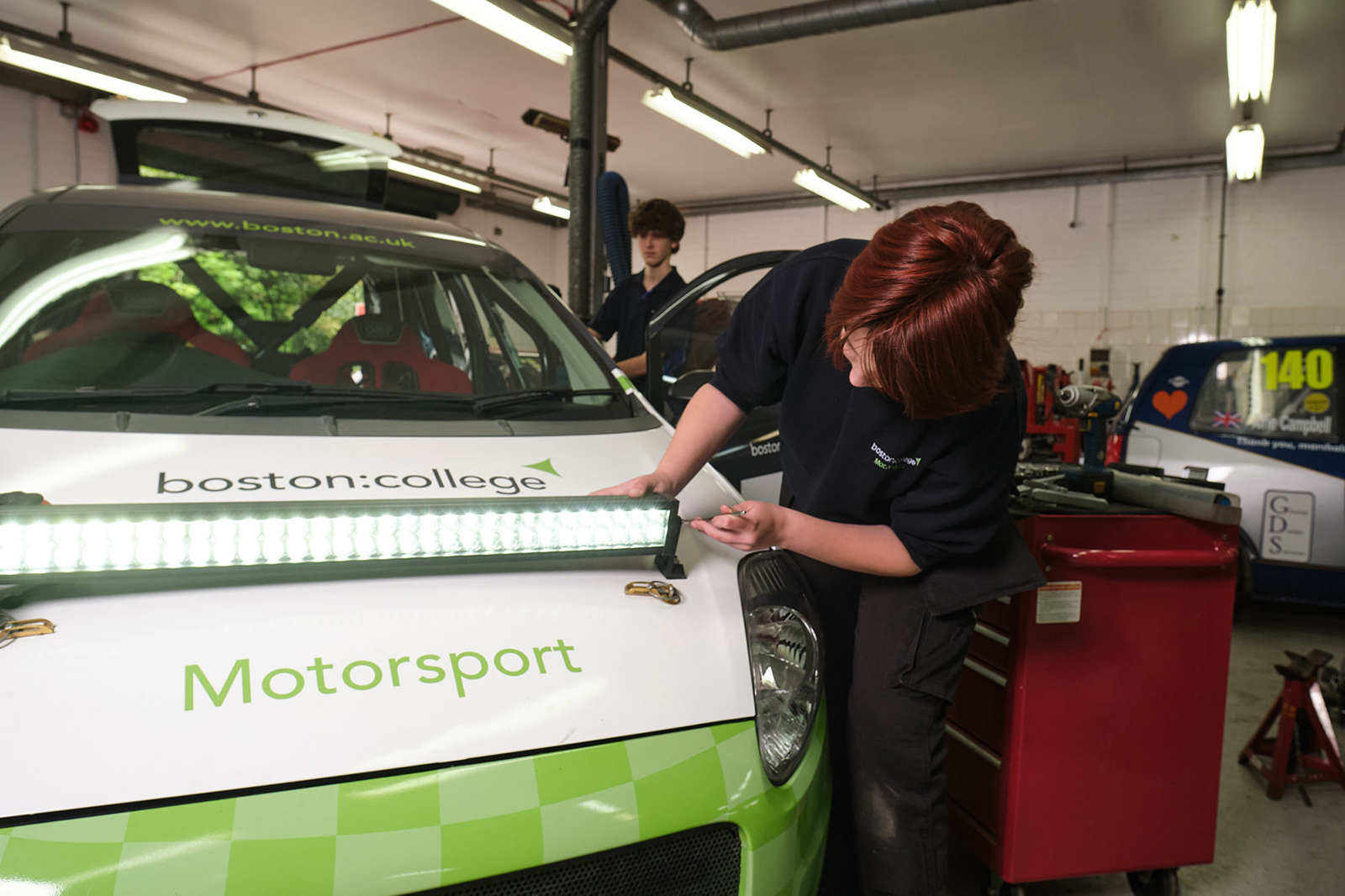 A student installing a light on a racing car.
