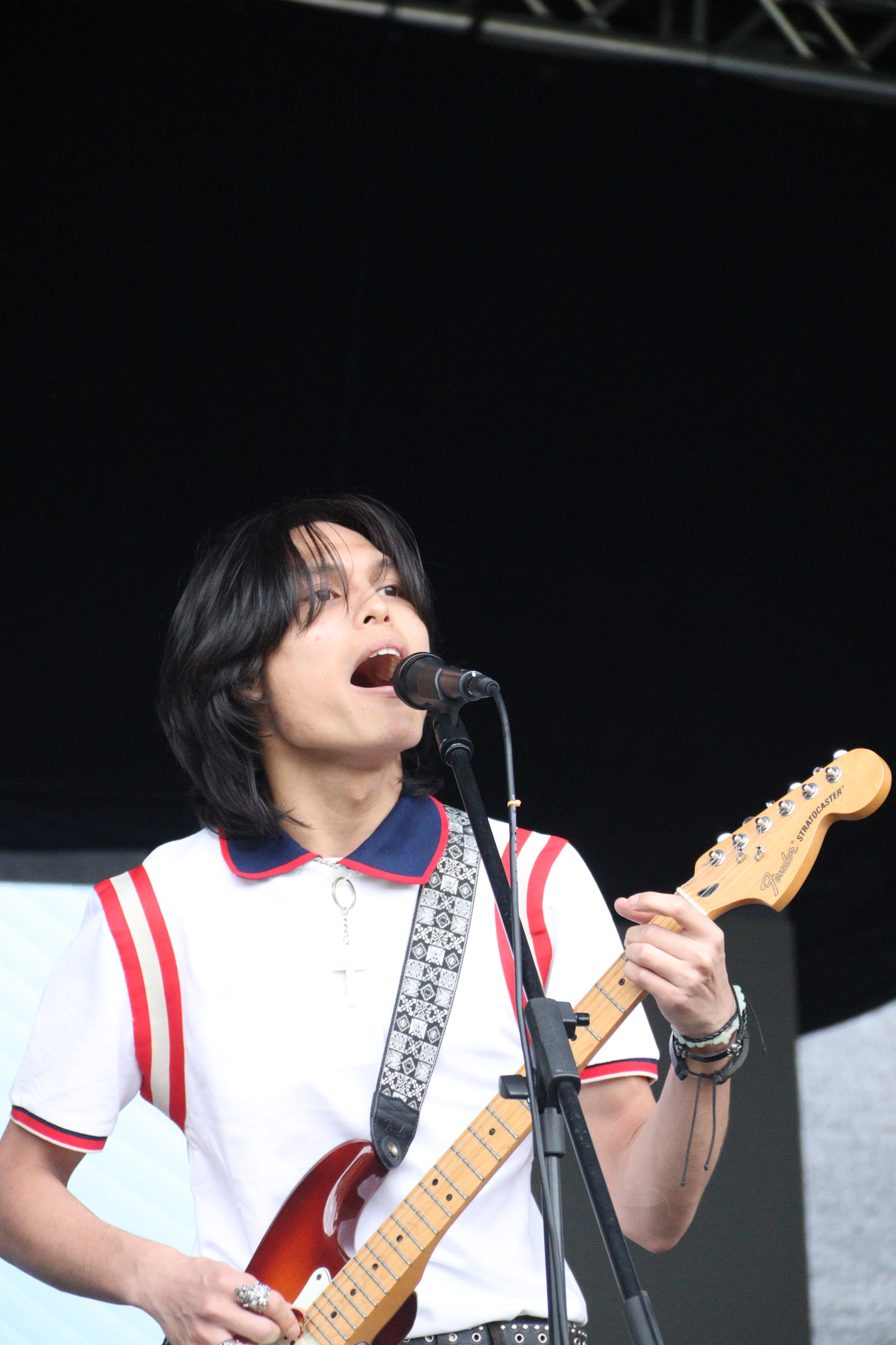 Student singing and playing the guitar on stage.