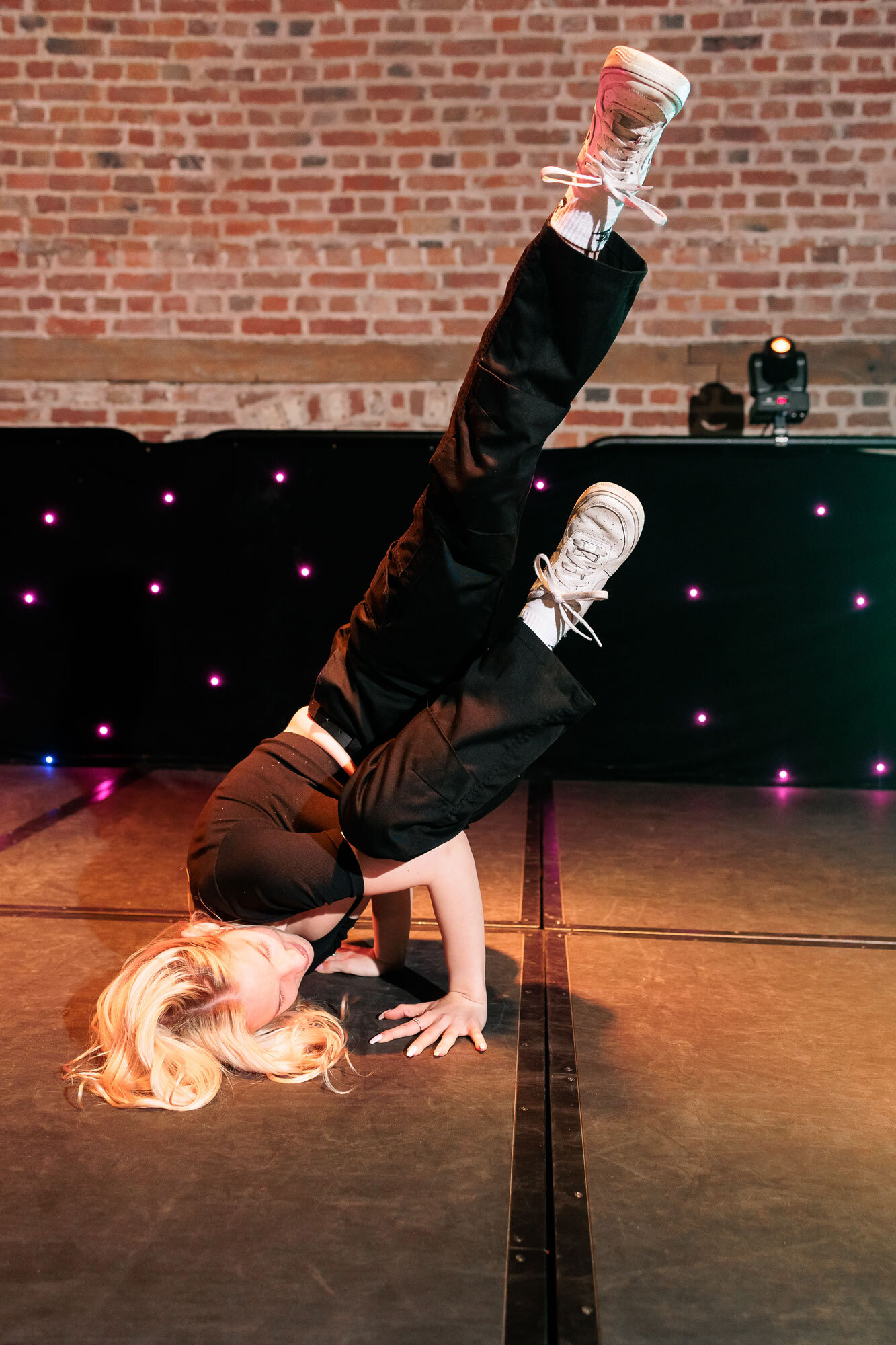 A student pushing themselves off the stage during a breakdancing routine.