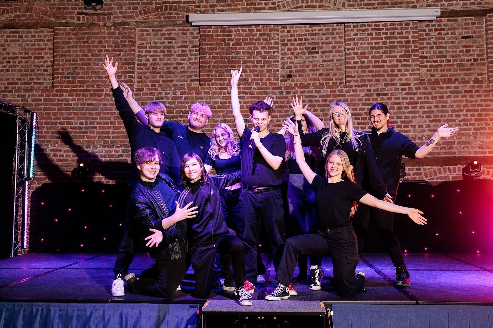 A group of students completing a song and dance routine on stage.