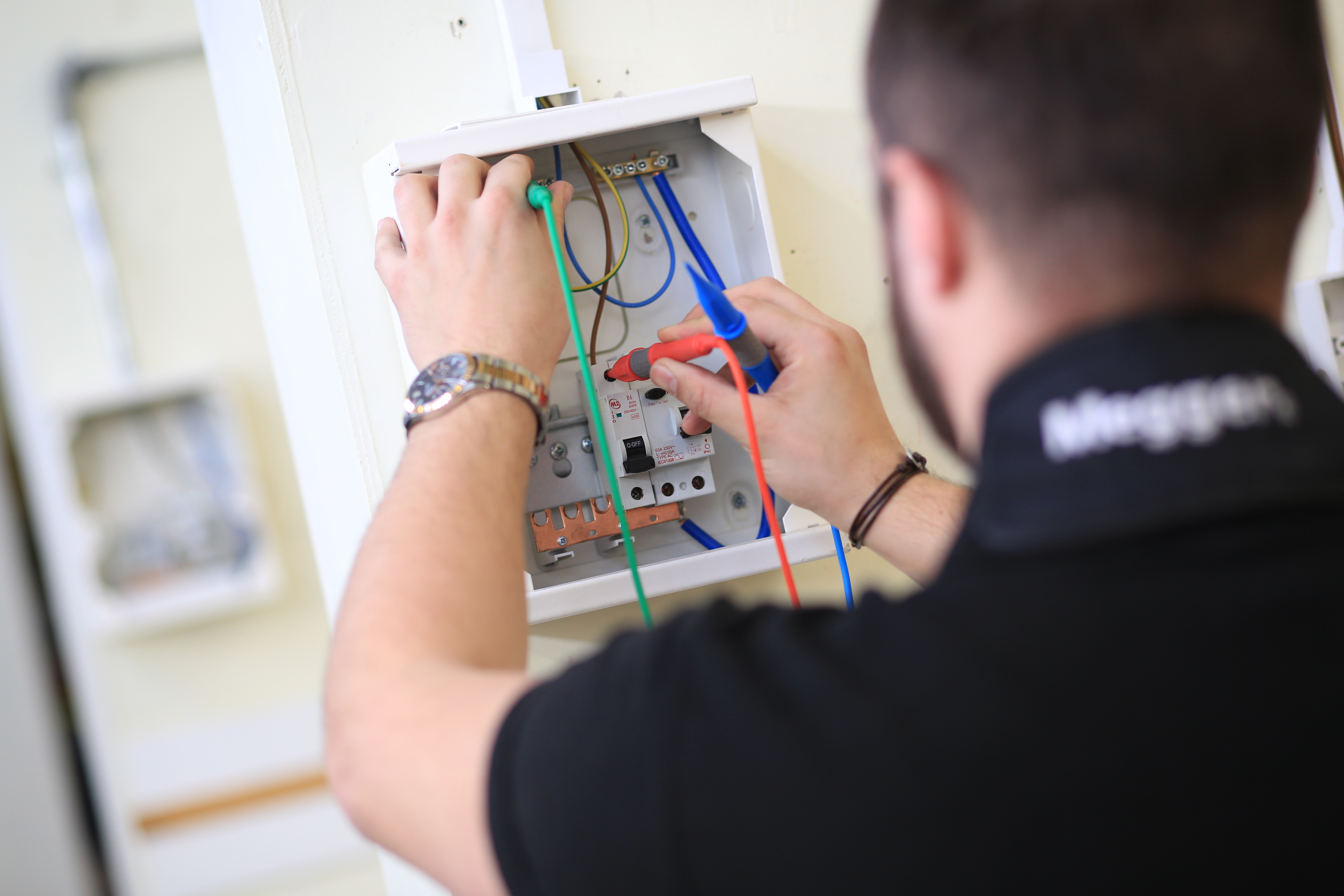 A person using tools to test an electrical socket.