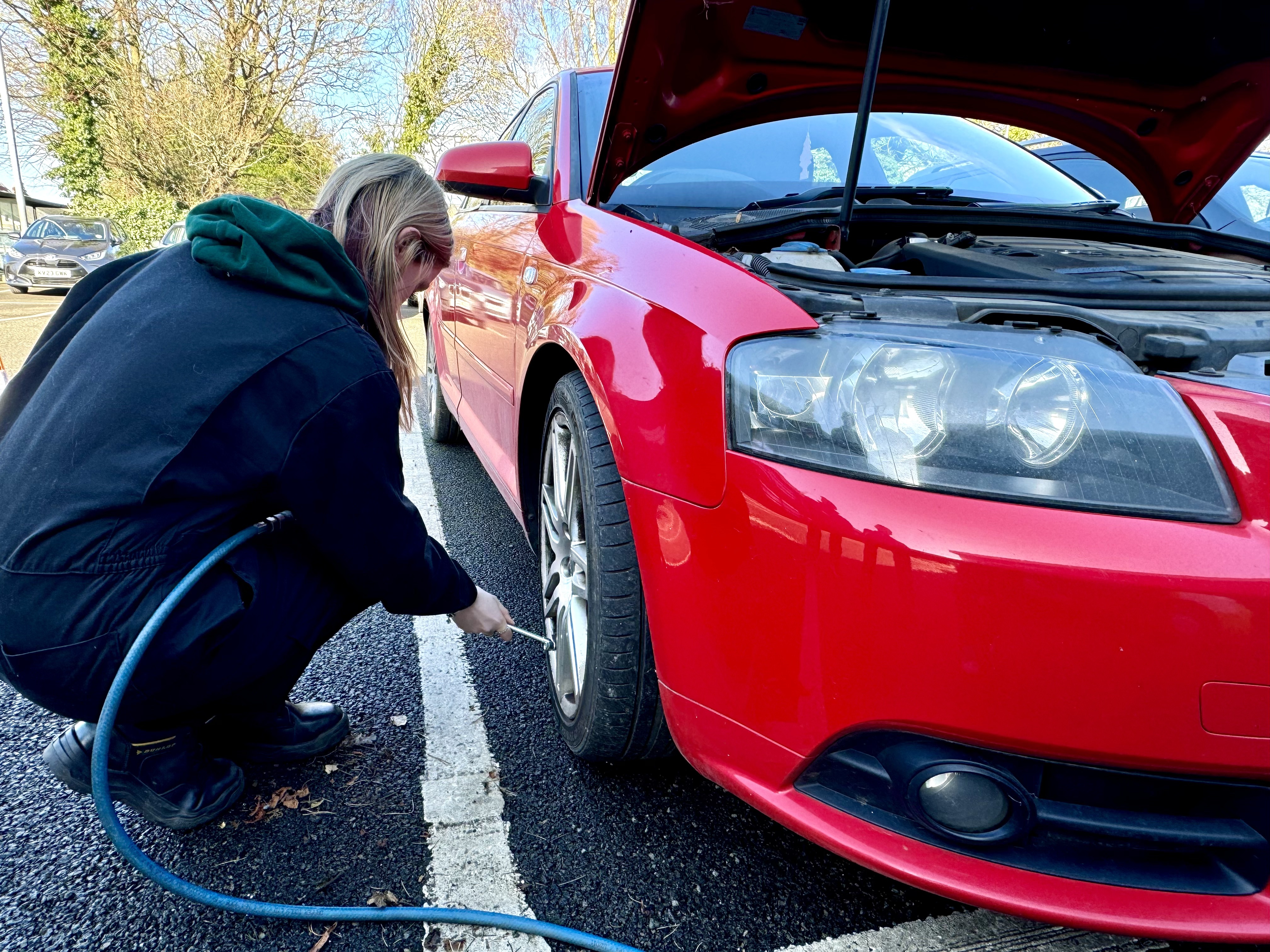 A student testing tyre pressures on a car.
