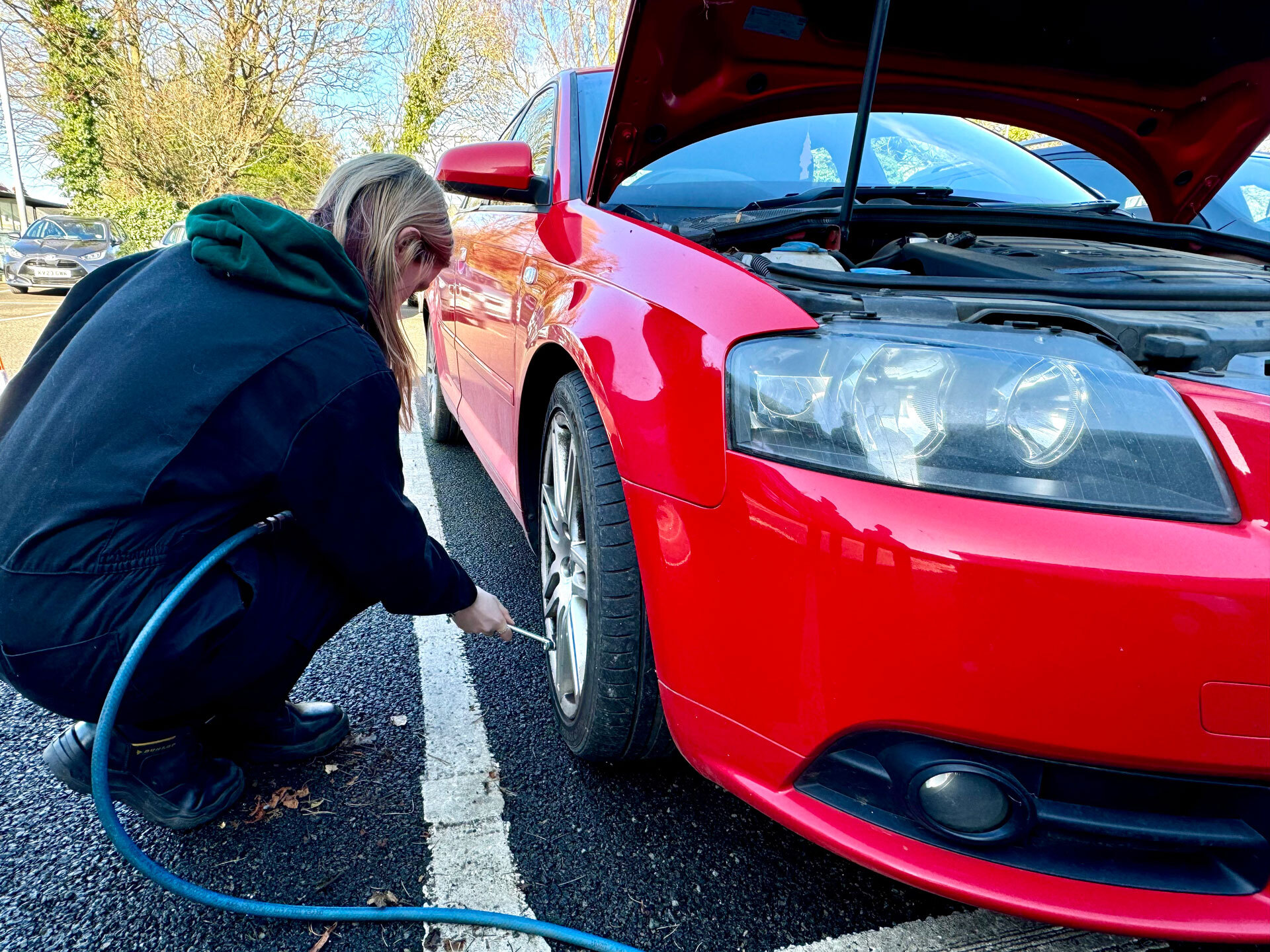 A student testing tyre pressures on a car.