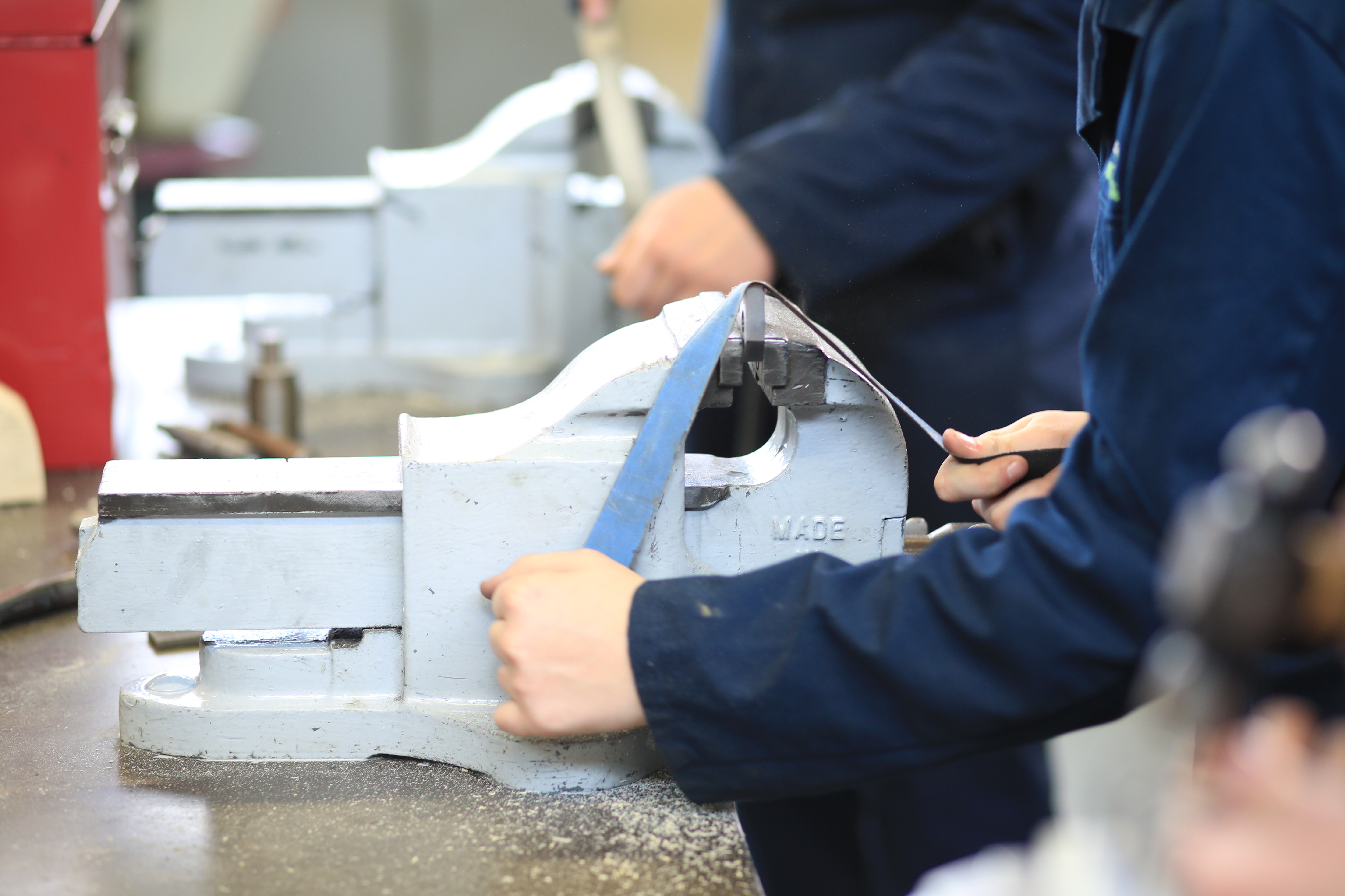 Students sanding down metal on a vice.