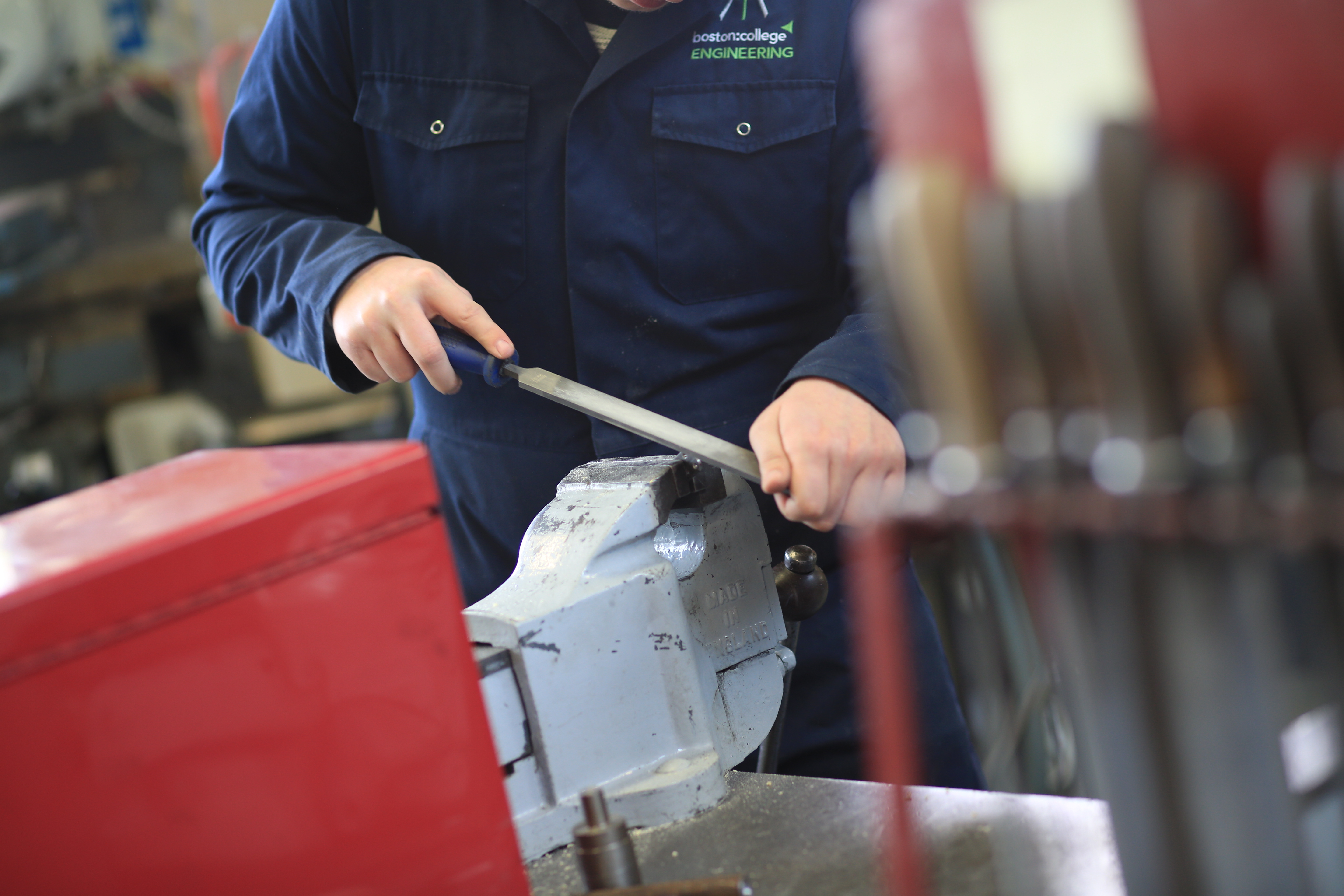 Students standing down an item using a vice in a workshop.