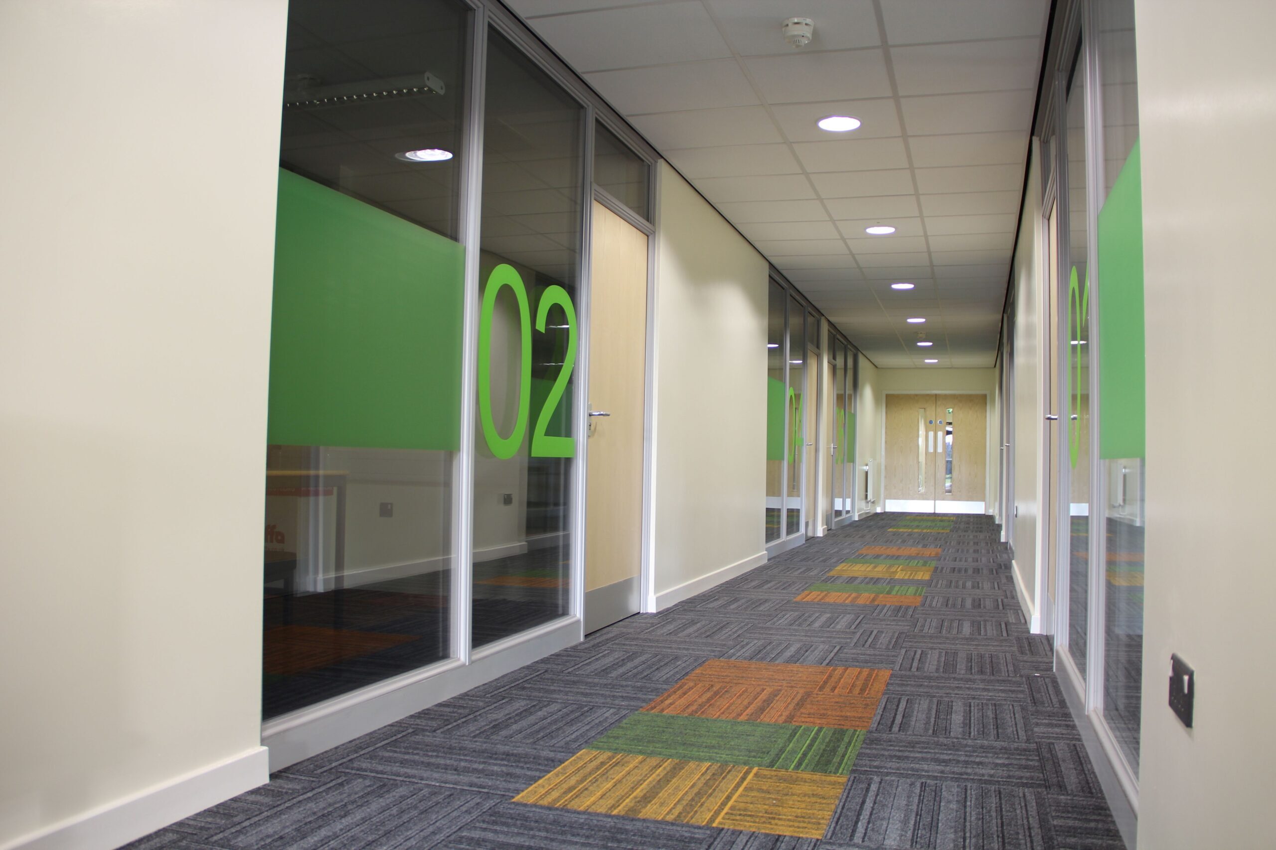 A corridor with green room numbers on the window.