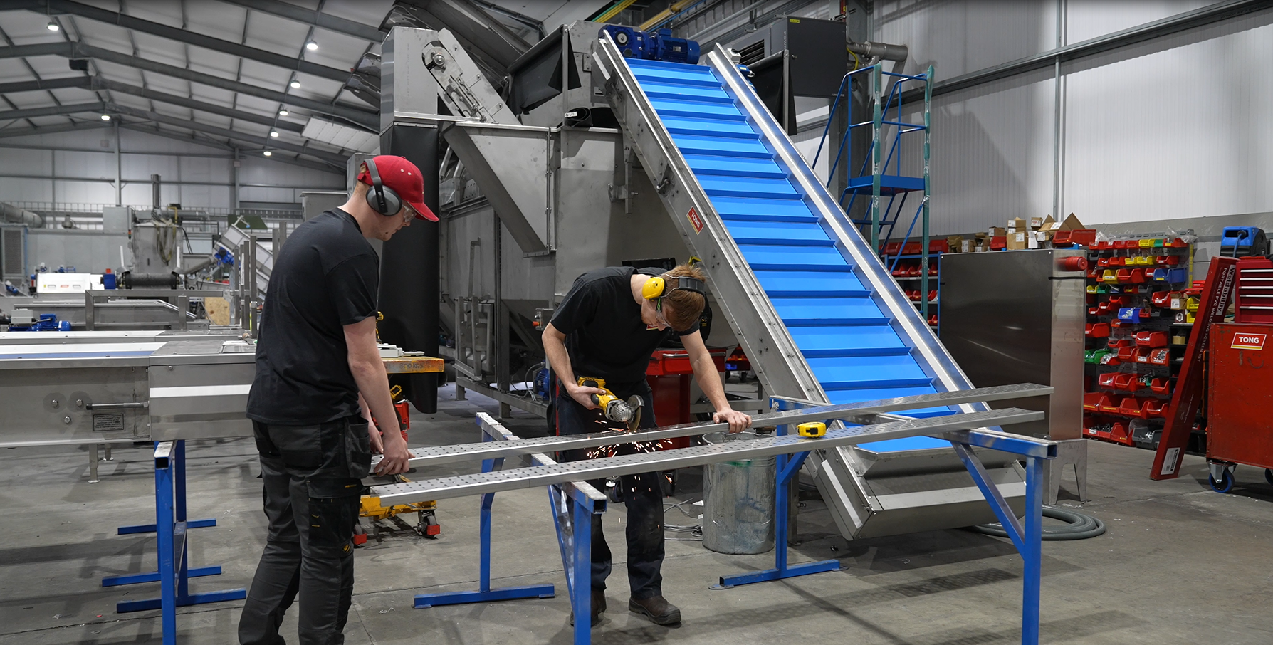 Two students working on a factory assembly line.