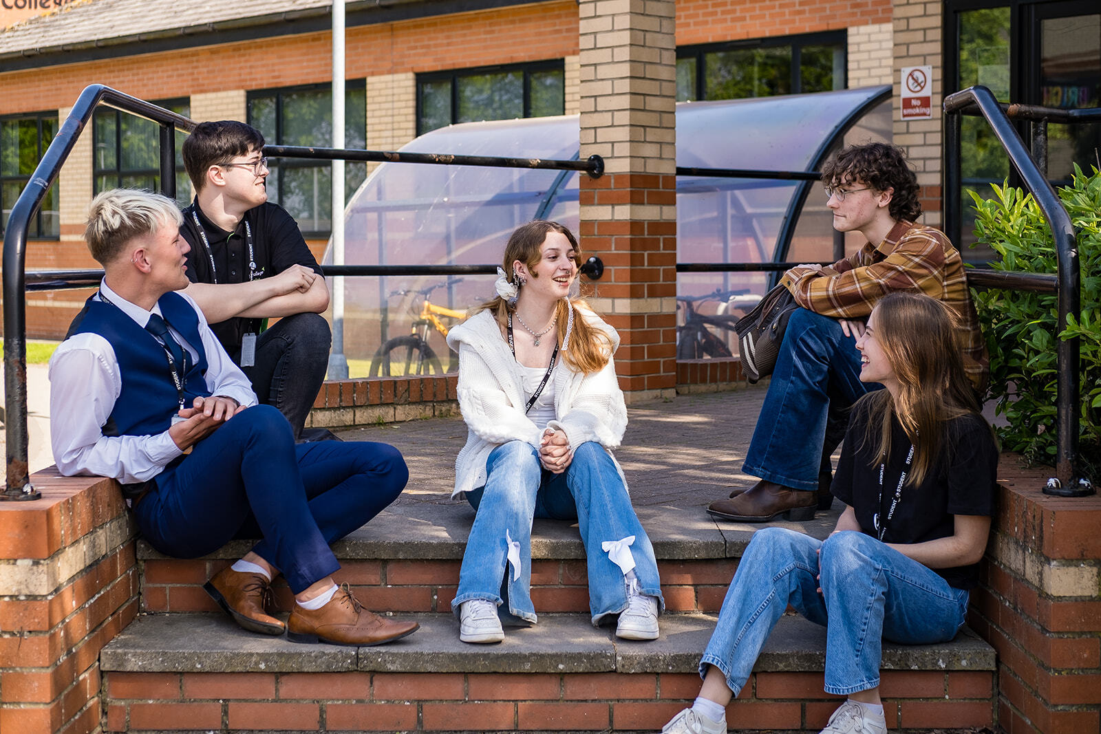 Five students sat talking on some steps outside a building.
