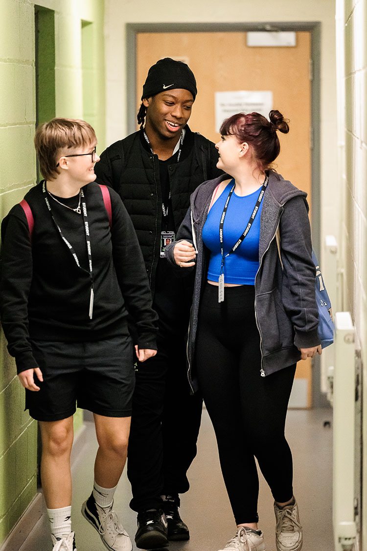 Students chatting and walking down a corridor.