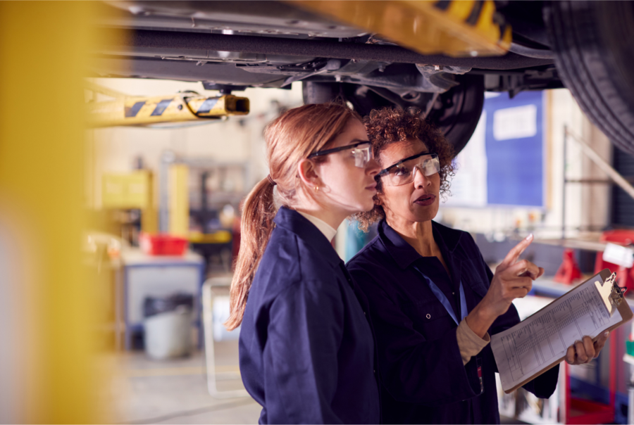 A student and lecturer inspecting the underside of a vehicle.