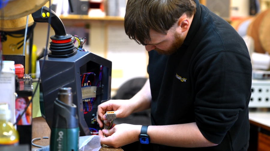 A student using tools at their workbench in a factory.