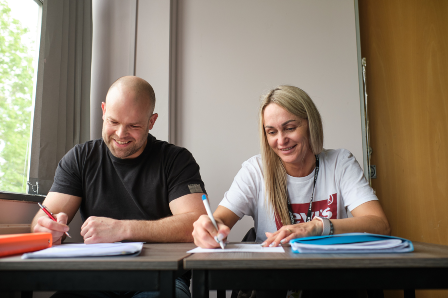 Two students sat a desk writing notes.