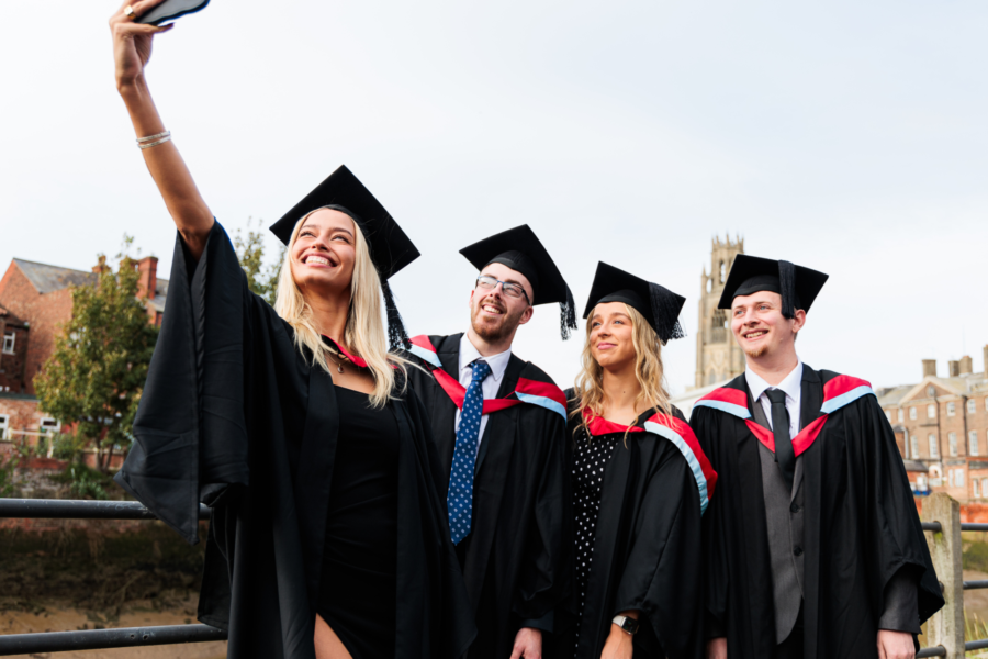 Student graduates taking a selfie at graduation.