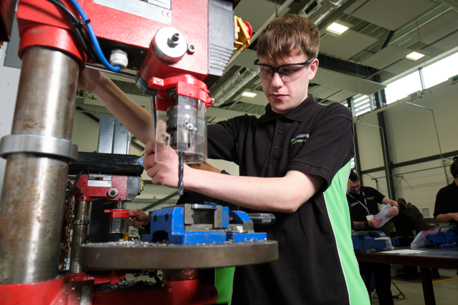 A student wearing safety glasses while working engineering machinery.