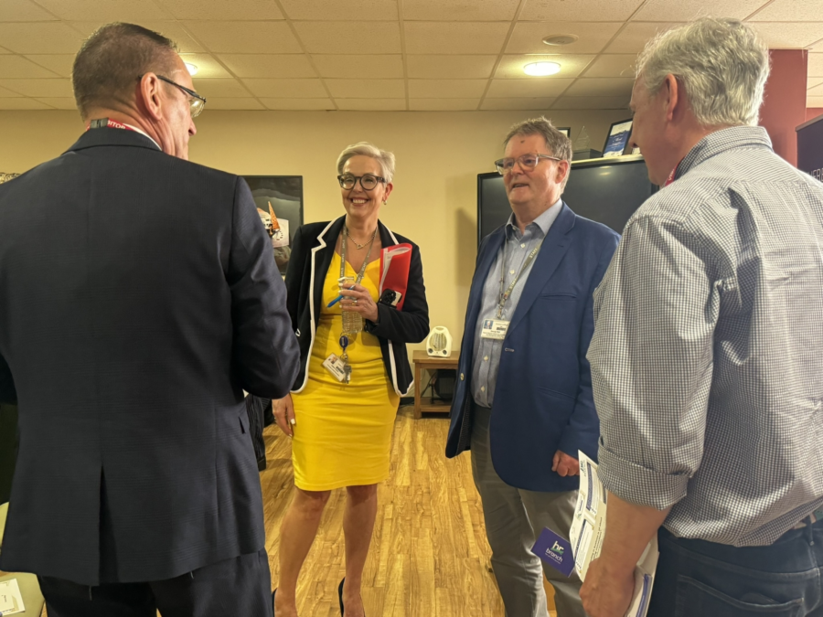 A group of business people stood talking in a group.