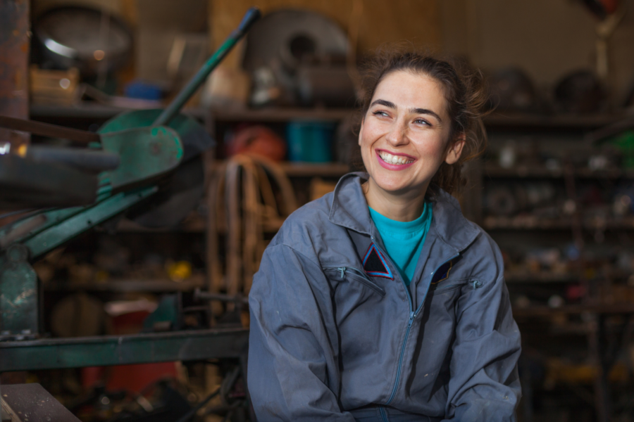 A student sat smiling next to factory machinery.